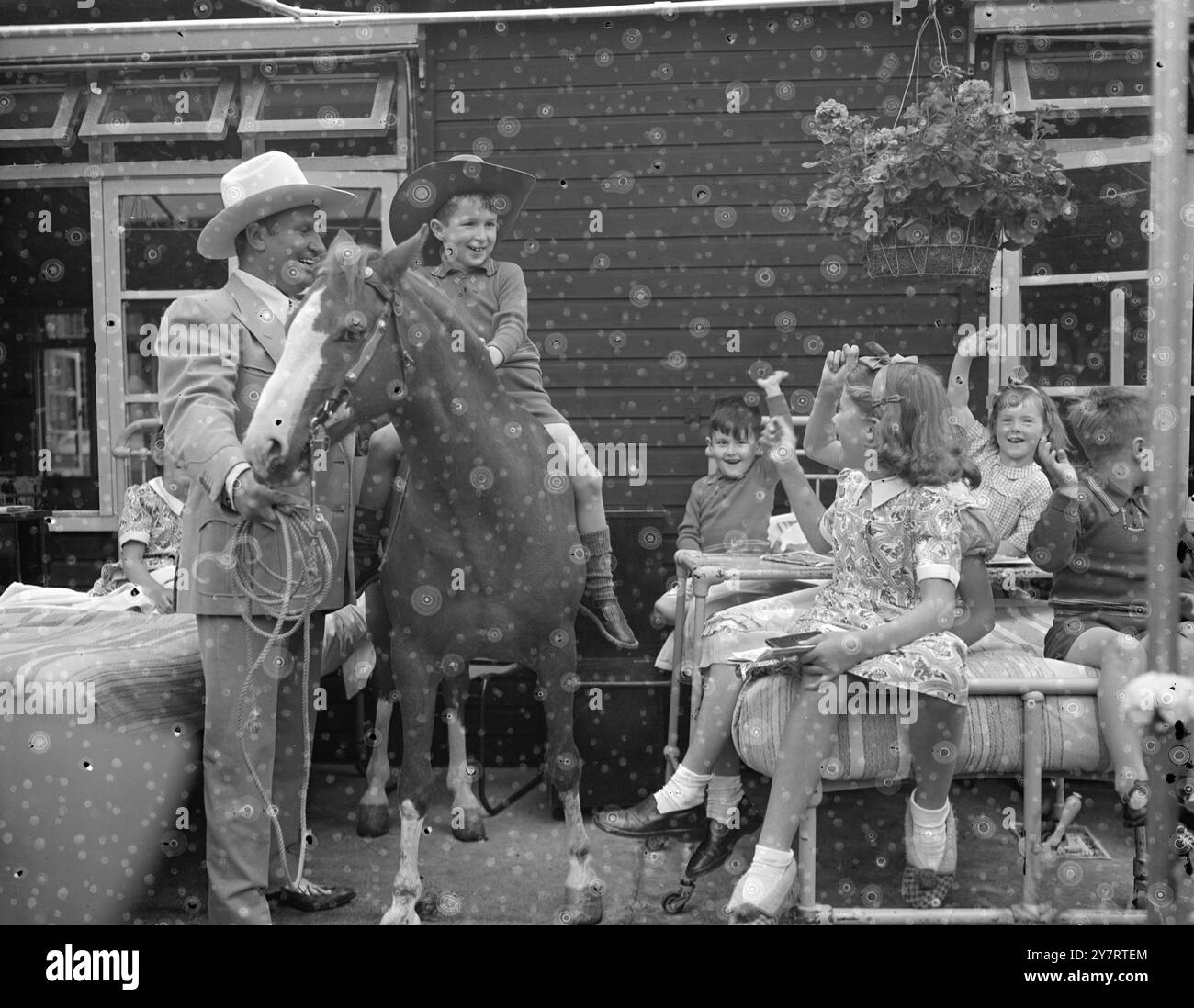 GENE AUTRY BESUCHT KRANKE KINDER 20.7,53. Cowboy-Filmstar Gene Autry, der am Wochenende in London ankam, besuchte heute Nachmittag Kinder im West Middlesex Hospital. Der Hauptzweck seines Besuchs war es, der Kinderstation des Krankenhauses ein Fernsehgerät zu präsentieren, das von den Lesern eines TV-Comics gekauft wurde. Paul Vincent, 8 Jahre alt, sitzt auf Little Champion, der von Gene Autry gehalten wird. 20. Juli 1953 Stockfoto