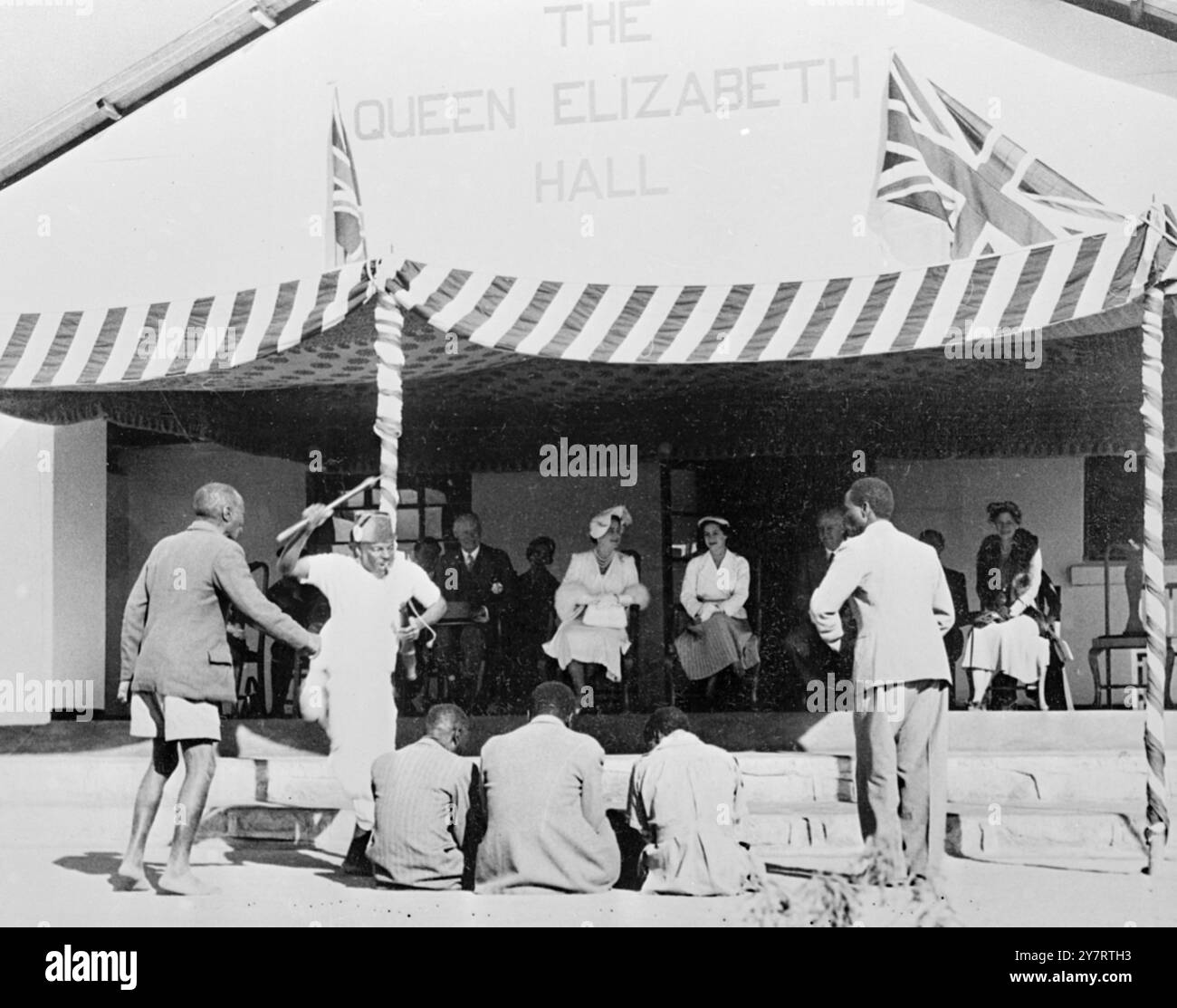 EINGEBORENE UNTERHALTEN KÖNIGLICHE BESUCHER (Originalunterschrift)Foto-Shows Queen Elizabeth the Queen Mopther und Prinzessin Margaret werden bei der Mangwende Agricultural Show in Mrewa von einheimischen Tänzern begleitet, begleitet von einer einheimischen Band, unterhalten. 16. Juli 1953 Stockfoto