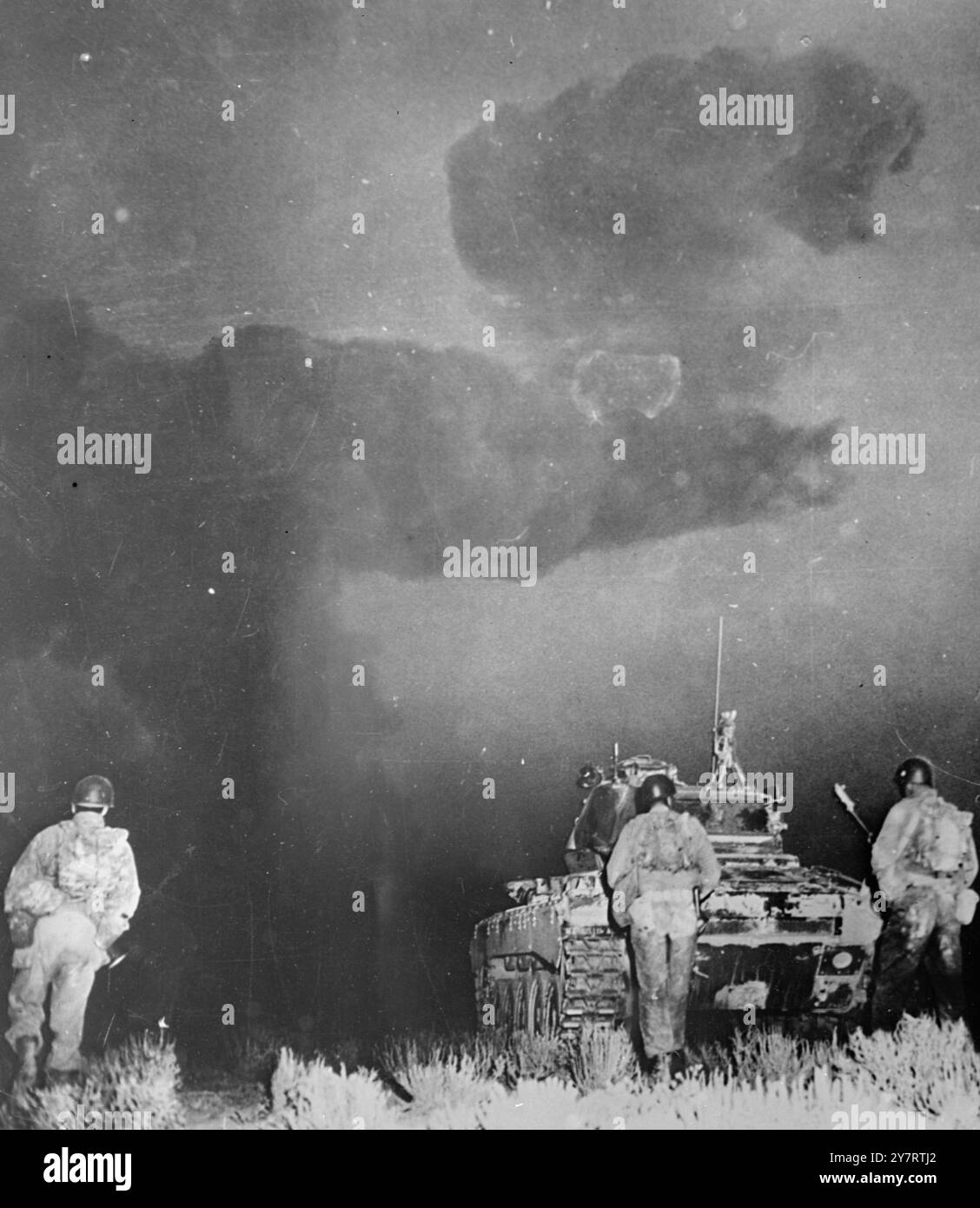 IN DER NÄHE VON 'GROUND ZERO' Yucca Flat, Nevada ..... Die sechste Armee von Camp Desert Rock bewegt sich hinter einem der Panzer, die sie nach der letzten Atomexplosion in Yucca Flat am 1. Juni in Richtung ' Ground Zero ' geführt haben. Die atomare Wolke sieht aus wie eine finstere Faust, die über Panzer und Männer in der Dunkelheit des Morgengrunds schwebt. Die Truppen waren 7000 Meter von der Explosion entfernt, als sie angegriffen wurde. Sie zogen in Richtung Ground Zero vor, bis sie durch radiologische Sicherheitsregeln gestoppt wurden. 4. Juni 1952 Stockfoto