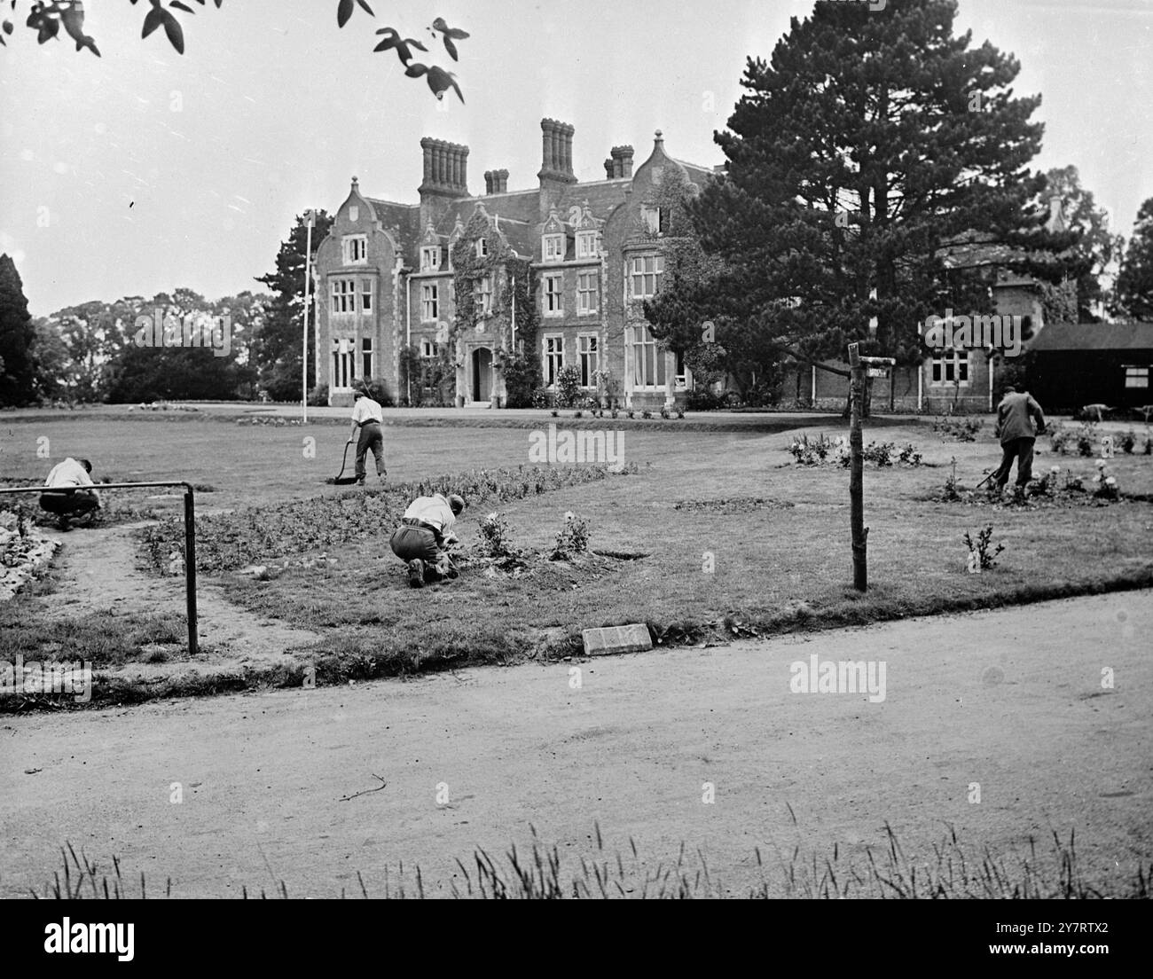 DAS NEUE GEFÄNGNIS FÜR MÄNNER OHNE GITTER. 9.7.53 H.M. Prison, Grendon Hall, Grendon Underwood, Bucks, wurde im Januar 1953 eröffnet. Es ist ein Mindestsicherheitsgefängnis für etwa 125 Männer, die entweder keine vorherige Strafe verbüßt haben oder noch immer als ausbilderfähig gelten und wahrscheinlich der Verantwortung für offene Bedingungen standhalten. Grendon Hall ist ein großes Haus, das auf einem weitläufigen Grundstück steht und entsprechend umgebaut und ausgestattet wurde. Das Foto zeigt die Vorderansicht der Grendon Hall mit Gefangenen, die auf dem Rasen arbeiten. 9. Juli 1953 Stockfoto