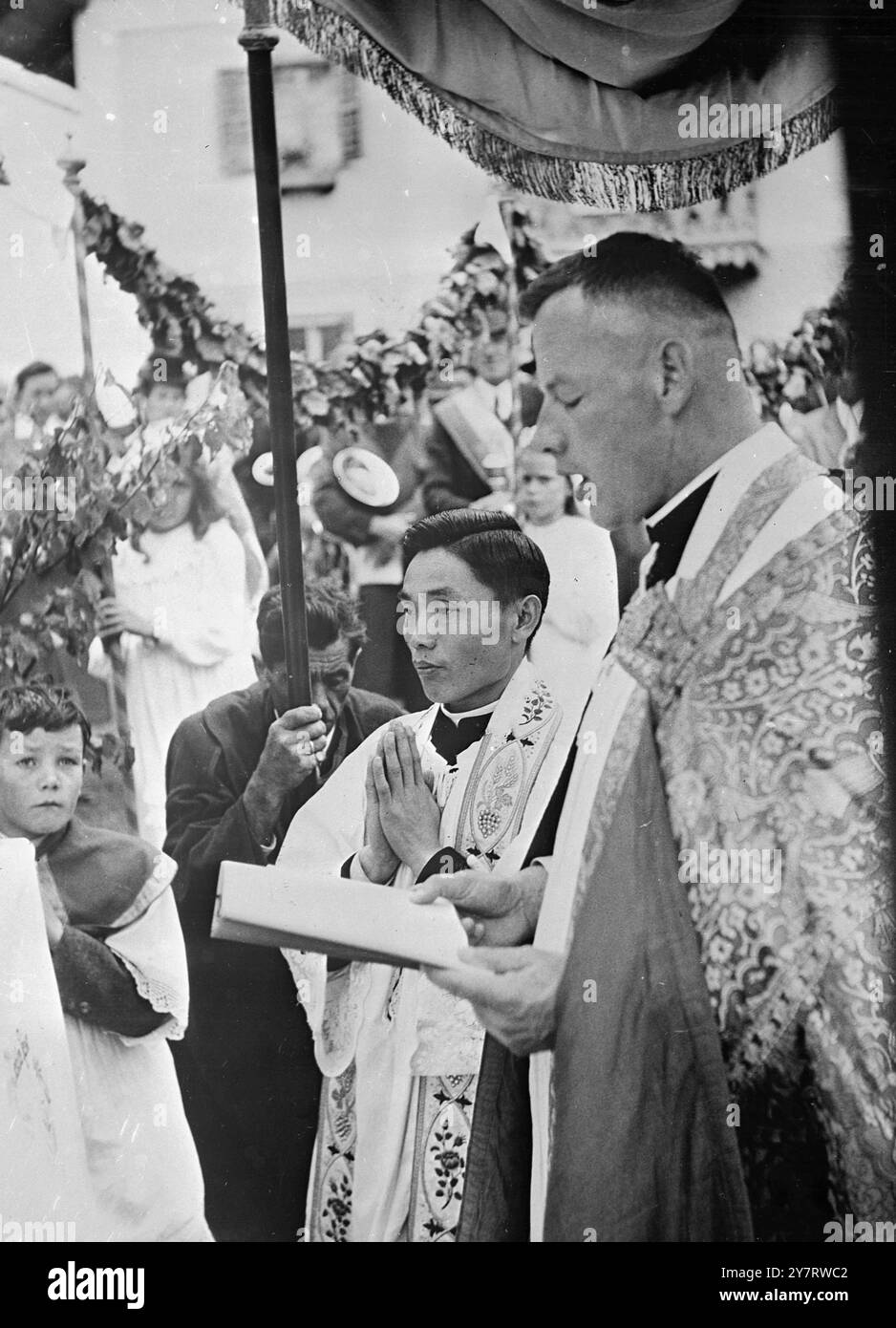 ÖSTERREICHISCHES DORF FLIEGT IN CHINESISCHEM PRIESTER 19.6,53. Der österreichische Sommerort Bramberg im Oberpinzgau zeigt anhand praktischer Beispiele, dass die Bande der Religion enger sind als die der Nationalität. Denn als der örtliche Priester kürzlich Hilfe brauchte, kam die Nachricht, dass ein chinesischer Priester, der jetzt auf den Philippinen lebt, den Job annehmen würde, aber dass es drei Monate lang keine freien Segelplätze gäbe. Die Bramberger sammelten das Fahrgeld für ihn, damit er mit dem Flugzeug kommen konnte, und „Unser kleiner Chinese“, wie sie ihn liebevoll nennen, ist jetzt ein vertrauter Anblick im Dorf. Das Foto zeigt das junge Chine Stockfoto