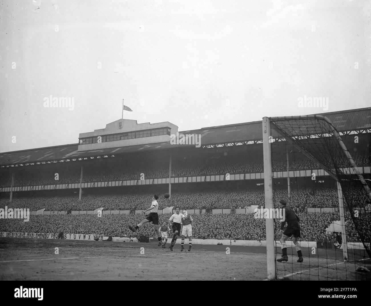 Die FUSSBALLVEREINE ZOLLEN DEN KING-FOTOSHOWS TRIBUT: Die Flagge fliegt heute Nachmittag auf dem Tottenham Hotspur Football Club Ground in Highbury, London, als Tottenham Arsenal spielte. Charlie Withers (Tottenham) wird den Ball anführen. Er trägt eine schwarze Armband als Hommage an König George VI. Andere Spieler, von links nach rechts: Don Roper (Arsenal), Alf Ramsay (Tottenham) und Reg Lewis (Arsenal). 9. Februar 1952 Stockfoto