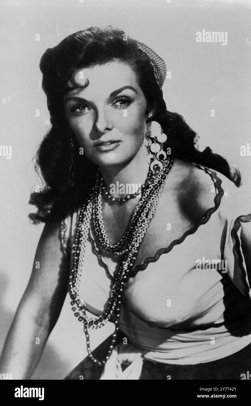 HOLLYWOOD, USA: FILMSTAR JANE RUSSELL IST MIT ARMREIFEN UND PERLEN FÜR IHRE ROLLE ALS ROMANI-FRAU IN DEM FILM HOT BLOOD (ARBEITSTITEL: TAMBOURINE) BELADEN. SIE SAGT, SIE WOLLTE SCHON IMMER EINE SOLCHE ROLLE SPIELEN, "MIT LAGERFEUERN UND DERGLEICHEN". 20. AUGUST 1955 Stockfoto