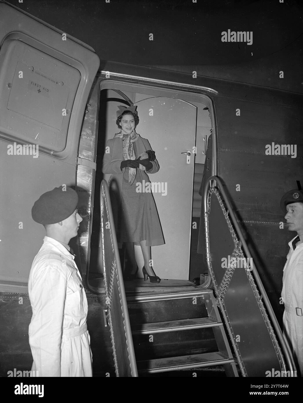 PRINZESSIN MARGARET FLIEGT NACH MALTA Prinzessin Margaret verließ heute den Flughafen London auf einem Wikingerflug nach Malta. Sie wird dort einen kurzen Urlaub mit Prinzessin Elizabeth und dem Herzog von Edinburgh verbringen, der vor Weihnachten nach Großbritannien zurückkehrt. Sie wurde von Lady Egerton begleitet, Lady in Warten auf Prinzessin Elizabeth. DAS BILD ZEIGT:  PRINZESSIN MARGARET , DIE von einem hellen gemusterten Schal gegen die Kälte gedämpft wird , in der Tür ihres Flugzeugs , bevor sie heute Morgen den Flughafen London nach Malta verlässt . 14. Dezember 1950 Stockfoto
