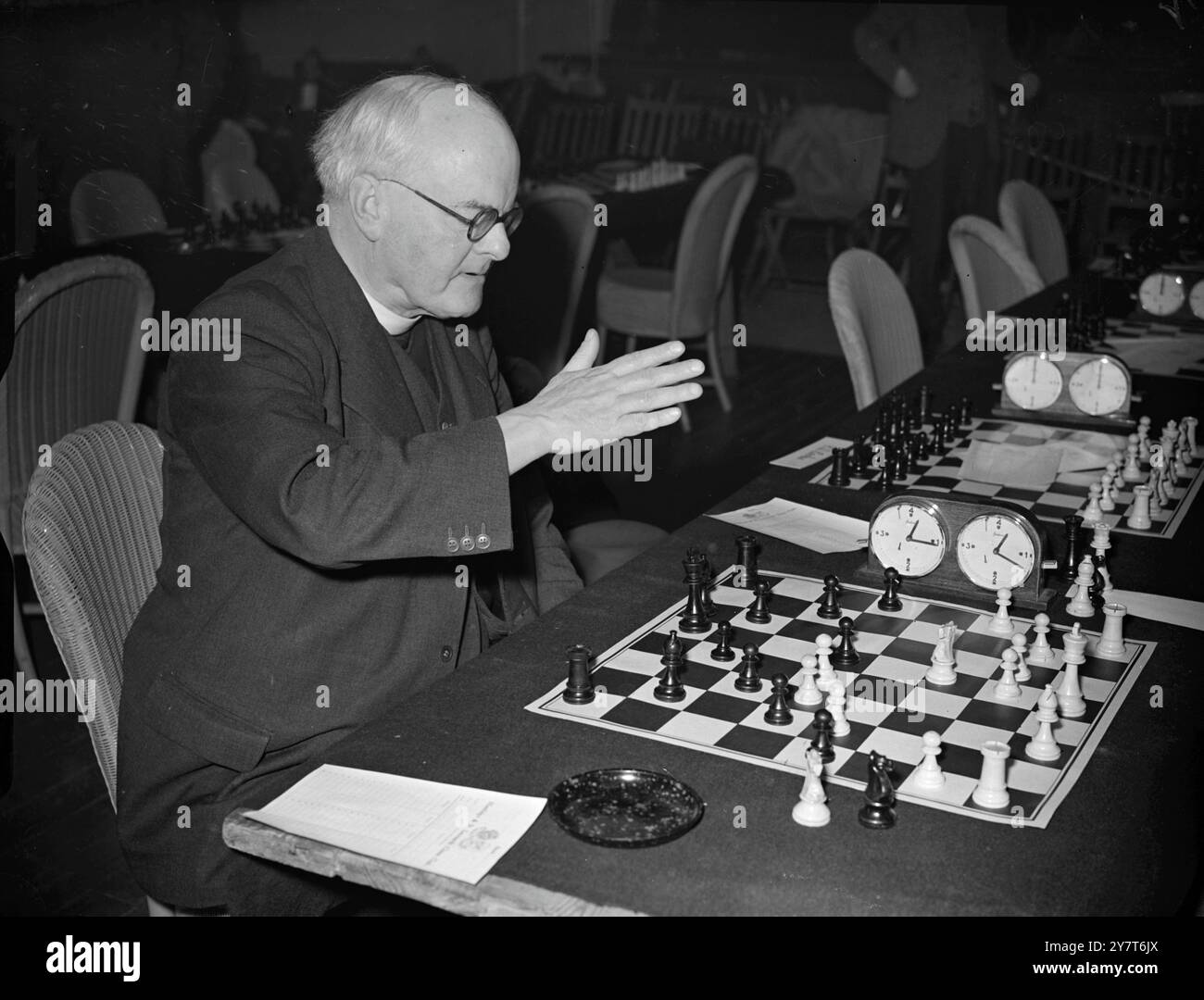 CHESS HAT SEINEN SEGEN der Reverend H.M. BLACKETT hebt seine Hand wie im Segen, aber er will nur eines seiner Stücke in einem steifen Match gegen Andrew Thomas auf dem 26. Internationalen Schachkongress im White Rock Pavilion , Hastings , Sussex bewegen . 28. Dezember 1950 Stockfoto