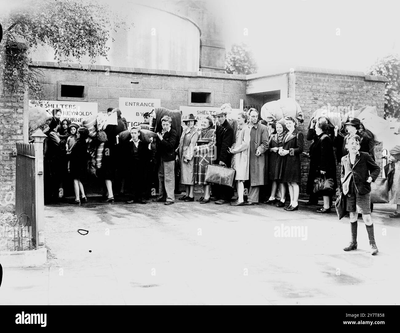 LONDONS ERSTE TIEFENUNTERKUNFT 1944die erste von einer Reihe von Tiefenunterkünften unter London wird von der Öffentlichkeit genutzt. Foto zeigt:- Leute stehen mit ihren Betten vor dem Tierheim an. 11. Juli 1944 Stockfoto