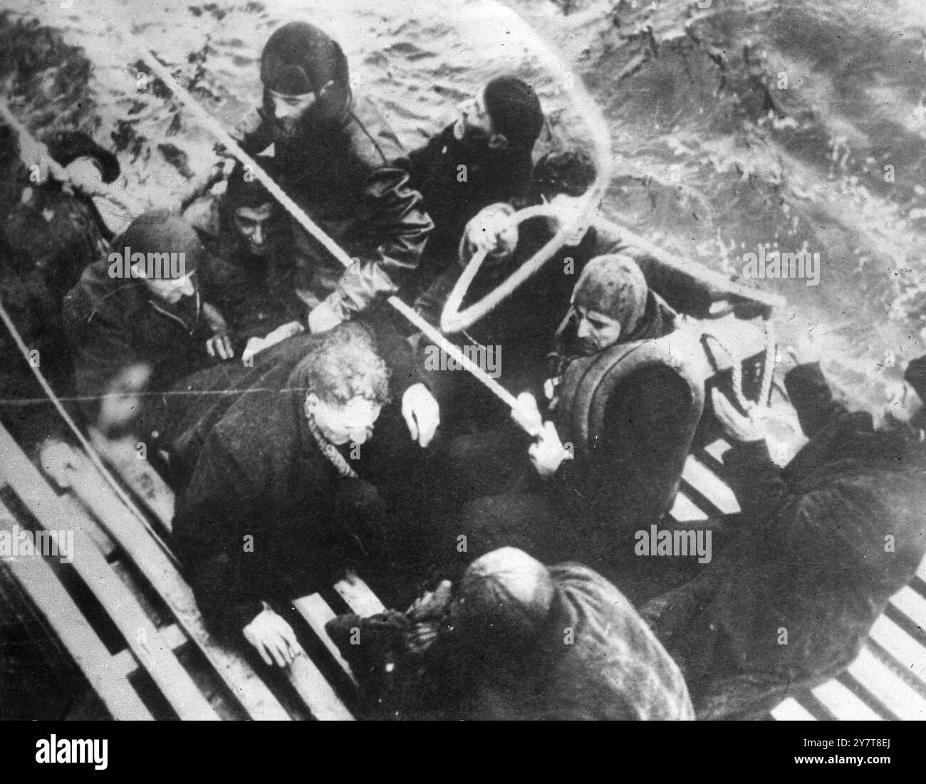 Die US-KÜSTENWACHE IM ATLANTIK RETTET 235 ERTRINKENDE MÄNNER 1944 U-Boote sind im Nordatlantik aktiv und dieses dramatische Bild wurde aufgenommen, als ein von Roy L. Raney aus Marblehead, Massachusetts, geführter Cutter der US-Küstenwache gefrorene Überlebende aufnahm, nachdem ein deutsches U-Boot ihr Schiff versenkt hatte. Für die Rettung von 235 Opfern aus zwei torpedierten Schiffen erhielt Captain Raney eine offizielle Auszeichnung. Das Foto zeigt: Überlebende des torpedierten Schiffes koppeln die Rettungsleine, als sie an Bord des Rettungsschneiders genommen werden. 30. Dezember 1944 Stockfoto