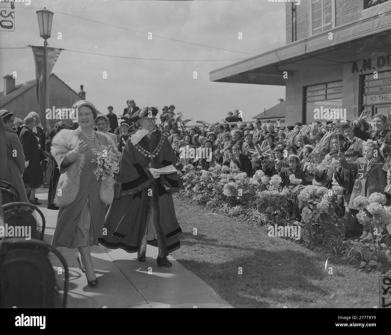 QUEEN MOTHER AT 10, WITHERSTON ROAD, LONDON LONDON: QUEEN ELIZABETH DIE QUEEN MUTTER SCHÜTTELT DIE HAND MIT DER 19-JÄHRIGEN STELLA COLE, BEOBACHTET VOM BÜRGERMEISTER VON WOOLWICH, ALDERMAN MRS. E. M. NEWMAN (RECHTS), WÄHREND EINES BESUCHS IM HAUS VON HERRN UND FRAU. FREDERICK COLE, 10 WITHERSTON ROAD, COLDHARBOUR HOUSING ESTATE, ELTHAM. HERR UND FRAU. COLES’ DREI WEITERE KINDER, MARTIN, 13 (LINKS), UND RICHARD, 12 UND ROBERT, 10, SIND EBENFALLS AUF DEM BILD. DIE KÖNIGSMUTTER BESUCHTE DIE GEMEINDE VON WOOLWICH'S COLDHARBOUR HOUSING ESTATE, UM SEINE FERTIGSTELLUNG ZU FEIERN, AM 9. MAI 1957 ZUSÄTZLICHES BILD - AUS EINEM SET VON 8 STÜCK Stockfoto