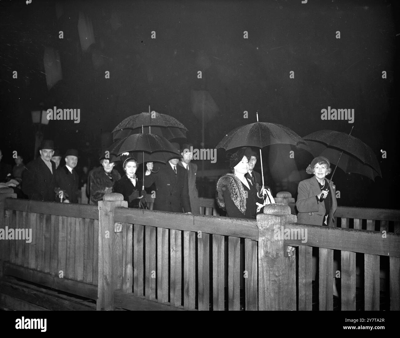 Die SCHWARZ GEKLEIDETE KÖNIGIN TRÄGT EINEN EIGENEN SCHIRM NACH DER REGNERISCHEN FLUSSFAHRT mit ihren eigenen Regenschirmen als Schutz vor dem kalten Herbstregen kommen die Königin und Prinzessin Margaret - beide in schwarz gekleidet in Trauer um den verstorbenen König Gustav von Schweden - nach ihrer Reise auf der Themse am Tower Pier in London an Land . Mit dem König waren sie zu Gast von Sir John Anderson , Vorsitzender der Port of London Authority , bei einem Flussbesuch einiger Docks . 31. Oktober 1950 Stockfoto