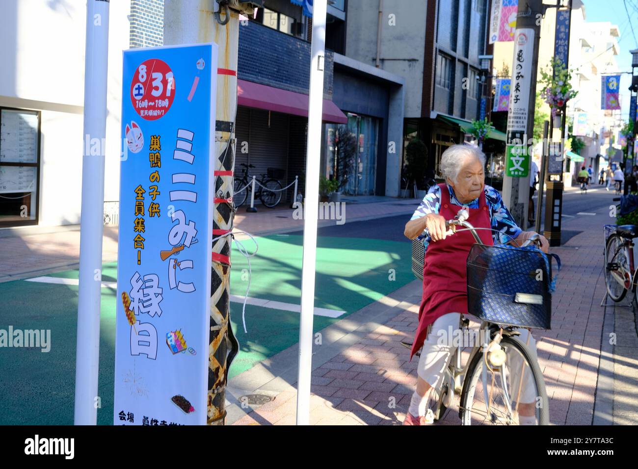 Eine ältere Frau, die auf der Sugamo Jizou-dori Shopping Street Fahrrad fährt. Toshima City, Tokio, Japan Stockfoto