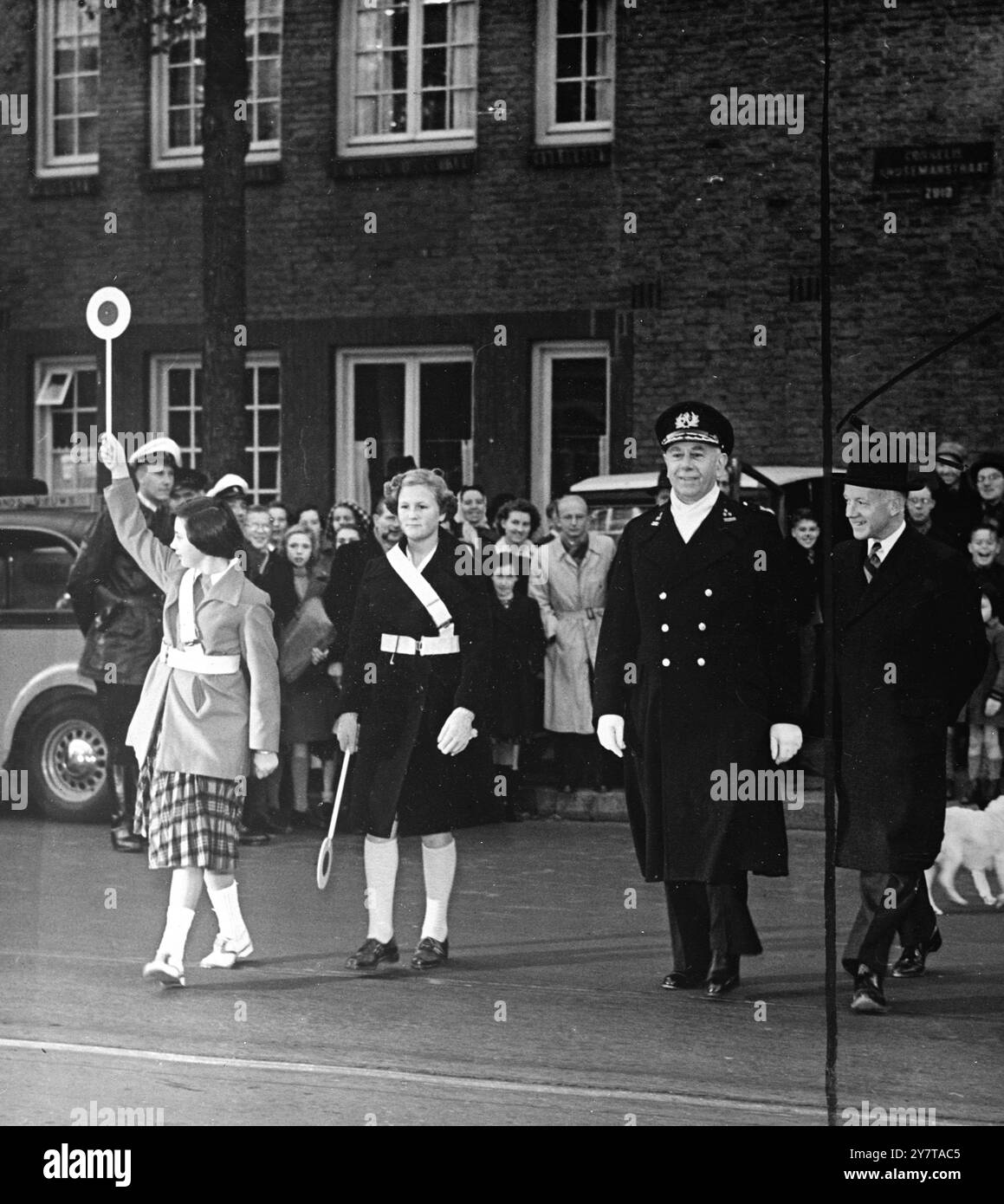 AUS DER BRATPFANNE IN SICHERHEIT, auf dem Weg zum "Spiegelei " in Sicherheit, ist Amsterdams Chefkommissar, Herr H. C. Kaasjagger , der von weißgürtigen Schulmädchen der 100. Verkehrsbrigade, die in der Stadt organisiert wurde, über eine geschäftige Straße begleitet wird. Das Personal, das die Mädchen bei sich tragen, hat den augenscheinlichen Spitznamen ( Spiegelei ) von niederländischen Bürgern bekommen : wird verwendet, um Fahrer zu signalisieren. Die Schulbrigade begleitet Kinder sicher über die Straßen vor und nach der Schulzeit. 9. Januar 1950 Stockfoto