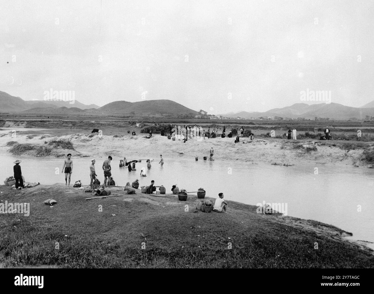 12. Mai 1950 an der Grenze zwischen britischem und chinesischem Territorium im Raum Hongkong werden neue Einwanderungskontrollvorschriften durchgesetzt. Die Vorschriften sollen verhindern, dass "unerwünschte" Personen nach Hongkong gelangen. Britische Offiziere erlauben jedoch normalen kleinen Verkehr, der nur einer Zollkontrolle unterliegt. Seit dem Inkrafttreten der Vorschriften wurden die Frauen mit Waffen zurückgedreht. Das Bild zeigt: Chinesen waten über den geschwollenen Fluss bei man kam To, um keine Steuern auf ihre Waren zu zahlen. Stockfoto