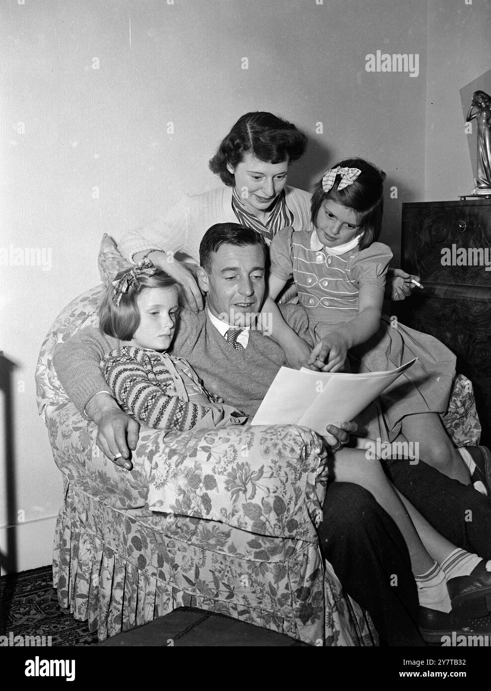 HOME IS THE HELD 30 April 1950 Reg Lewis, Held von Arsenals 2-Null-Sieg gegen Liverpool gestern im FA-Cup-Finale in Wembley, untersucht heute (Sonntag) Pressebilder des Spiels mit seinen achtjährigen Töchtern Anne (links) und Carol in ihrem Haus in Southgate, London. Im Hintergrund ist Mrs. Lewis. Der phänomenale Arsenal in Linke erzielte beide Tore seines Teams. Anne und Carol, die Zwillinge mit auburn, hörten die Exploits ihres Daddys auf dem Funkgerät. Stockfoto