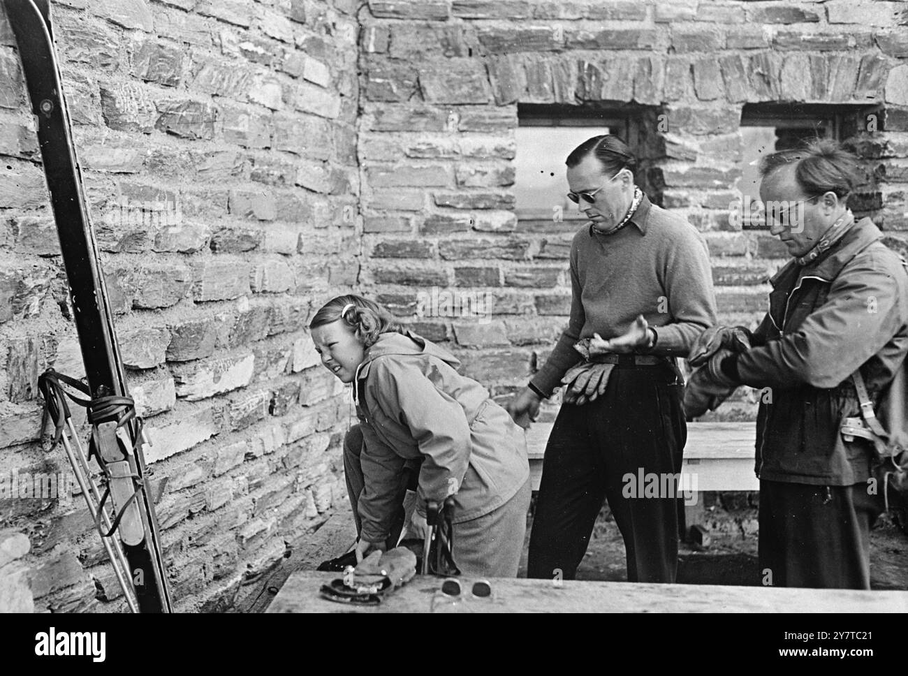 PRINZESSIN SPÜRT DEN KNALL am 4. April 1950 während ihr Vater Prinz Bernhard von den Niederlanden (Mitte) seinen Rat anbietet, kümmert sich Prinzessin Beatrix im Val d’Isere, Südostfrankreich, um einen engen Schuh. Prinz Bernhard, Königin Juliana und ihre beiden älteren Töchter, die Prinzessinnen Beatrix und Irene, machen im Isere-Tal Urlaub. Stockfoto
