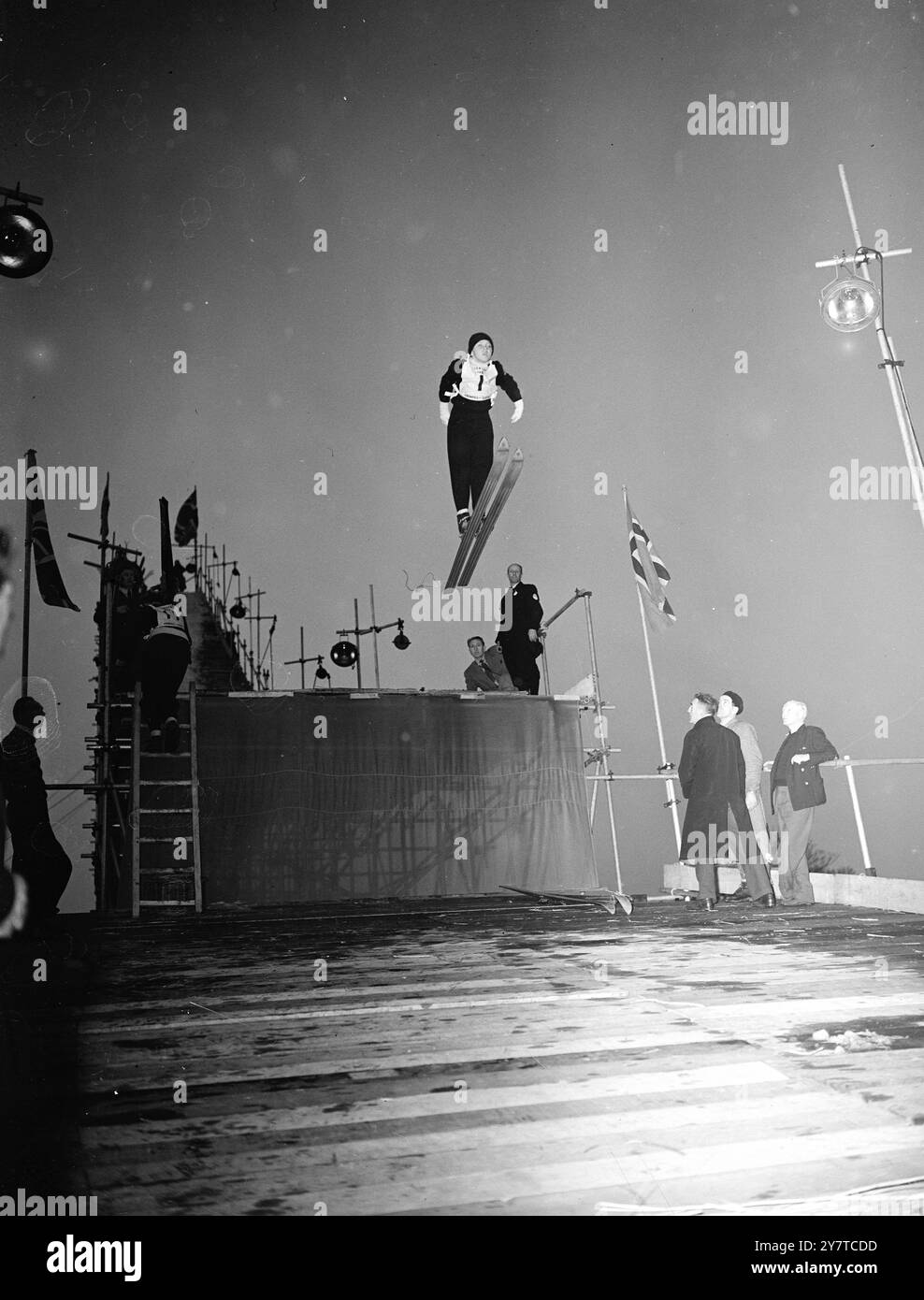 DER JÜNGSTE COMPITITITOR JAN DAG STOA des Koll Club 13-jährige Maskottchen des 25-köpfigen norwegischen Skisports schwingt heute Abend während des ersten britischen Skisprungwettbewerbs in der Luft der Hampstead Heath (London). Jan gilt als ein hervorragender Boyspringer. In diesem Jahr gewann er die norwegische Meisterschaft. Schnee für die Skipisten wurde aus Norwegen für den Wettbewerb importiert, und die Skifahrer verbringen den Großteil des Tages damit, ihn auf einer speziell dafür konstruierten Skipiste über eine Strohdecke zu legen. Trotz des milden Frühlingswetters wird der Wettbewerb morgen fortgesetzt. 24. märz 1950 Stockfoto