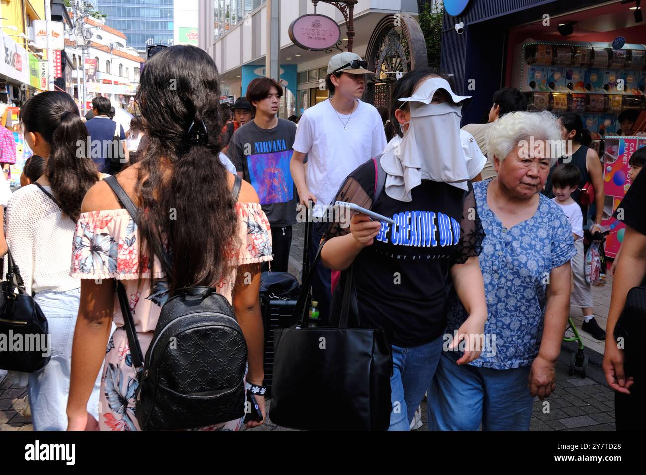 Eine Frau, die einen Sonnenschutz trägt, läuft in der Takeshita Dori Street, Harajuku, Shibuya Ward. Tokio, Japan Stockfoto