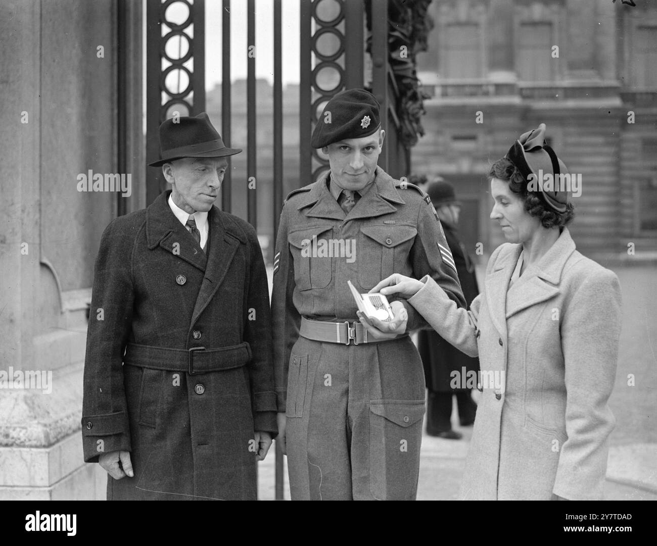 SERGEANT BEKOMMT G.M. BEI DER EINSETZUNG im PALAST Sergeant R. Warwick zeigt seinem Vater und seiner Mutter die George-Medaille, die er gerade vom König bei der Einsetzung im Buckingham Palace erhalten hatte. 14. März 1950 Stockfoto