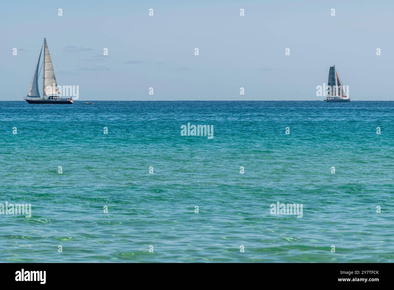Zwei Segelboote am Horizont segeln in entgegengesetzte Richtungen auf dem blauen Meer Stockfoto