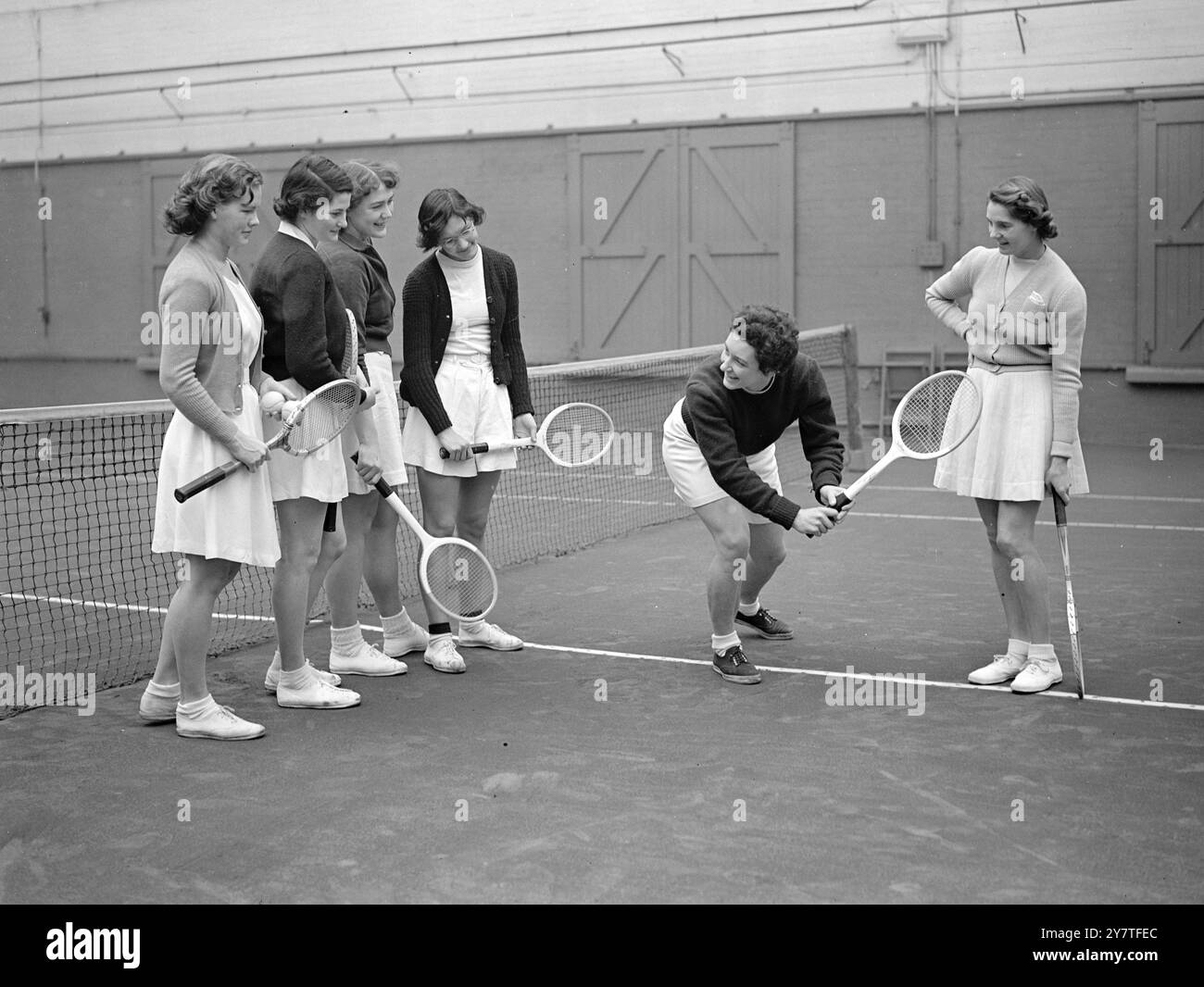 MÄDCHEN, DIE SIE ZURÜCKLÄSST, UM am 4. Februar 1950 AN DIE FRONT ZU KOMMEN. Später in diesem Monat verlässt Frau M. Menzies ( Kay Stammers ) Großbritannien, um in Südafrika zu leben. Vor ihrer Abreise tut sie so viel wie möglich im Trainingszentrum Maida Vale (London), wo unter ihrer Leitung Mädchen, die im Talentspottungsprogramm der Lawn Tennis Association entdeckt wurden, ein spezielles Coaching erhalten. Auf diesem Bild sieht Mrs. Menzies (ganz rechts), wie ihre stellvertretende Coach Wightman Cup-Spielerin Mrs. N W ( Molly ) Blair den Schülern im Maida Vale-Zentrum einen Rückhandschlag demonstriert. Es ist zu hoffen, dass Juniorspieler jetzt bei sind Stockfoto