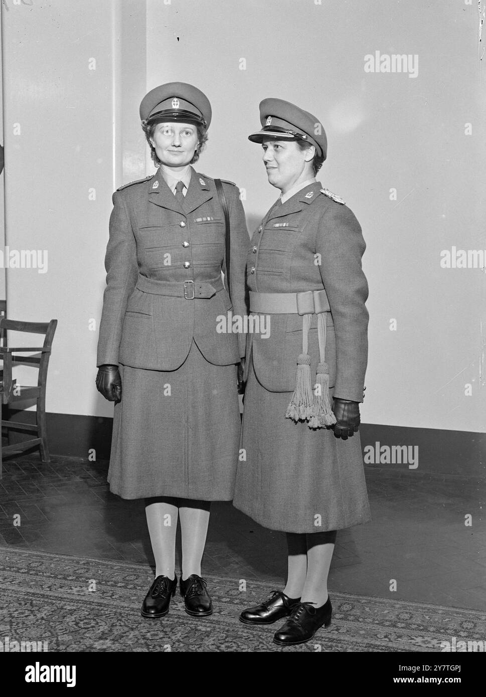 NEUE UNIFORMEN für das Women's Royal Army Corps und das Royal Army Nursing Corps von Queen Alexandra wurden im Whitehall Place, London gezeigt. Links ist die nicht-zeremonielle Kleidung der Subaltern und rechts die zeremonielle Uniform für einen Feldbeamten. Das traditionelle Grau und Scharlach wurden beibehalten, obwohl das Grau dunkler ist. Jacke und Rock sind in Barathea. 4. November 1949 Stockfoto