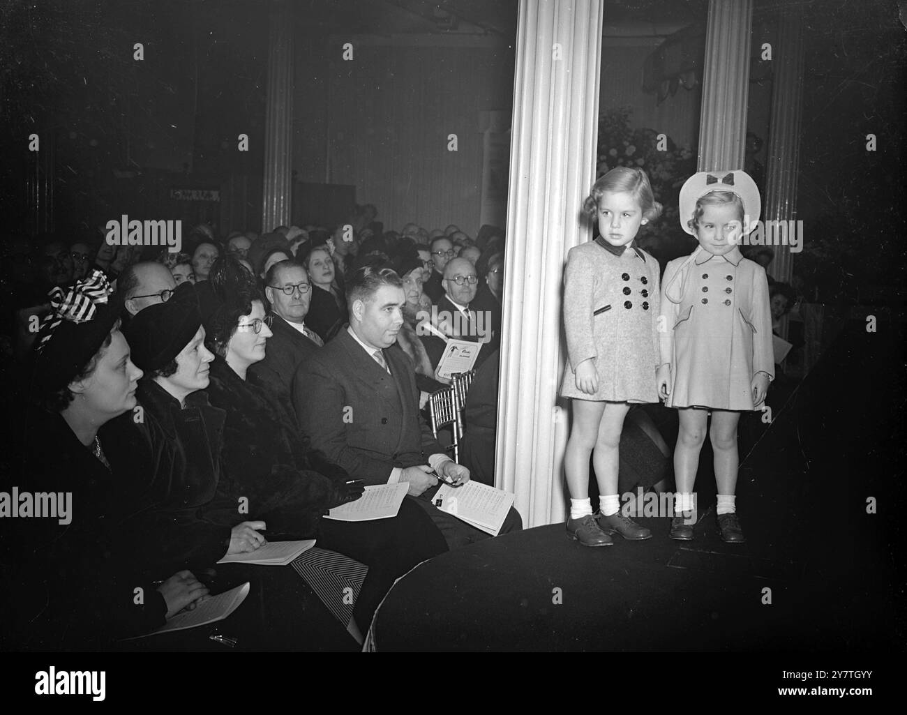 DIE JÜNGSTEN SCHAUFENSTERPUPPEN HABEN in der Welt der Mode eine gewisse AUSGEGLICHENHEIT UND CHARME, die Zeit hat eine eigene Bedeutung: Die Zukunft wird stark betont. Dies wurde heute in London gezeigt, als Cooks of St Paul's ihre Frühlings- und Sommermode für das Jahr 1950 präsentierte. DAS BILD ZEIGT:- die jüngsten Models auf der Cooks of St Paul's Modeschau in London heute mit Jennifer und Susan Baker, 3 1/2 Jahre alte Zwillinge aus West Finchley, London. Jennifer (links) trägt einen Schleife-Peep-Model-Mantel in fantasievollem Tweed. Susan trägt einen Mantel und eine Mütze aus Wollvelours. 31. OKTOBER 1949 Stockfoto