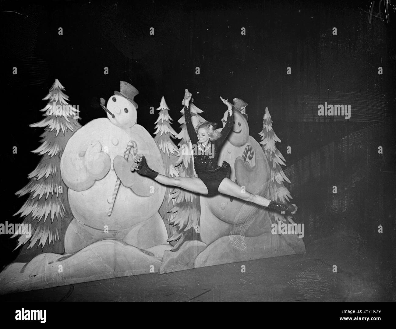 Peggy Wallace aus Brooklyn, New York - Weltmeister im Eiskunstlauf-Roller 1947 - macht die " Splits " vor dem Hintergrund von unbesonnenen Schneemännern in dem Millionen-Dollar-Roller " Skating Vanitties of 1949 ", inszeniert im Empire Pool , Wembley11 Juni 1949 Stockfoto