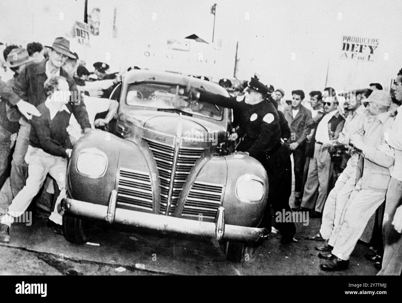 Filmstars stürzen die Streifenlinien des Studios Foto zeigt: Streifenposten stürmen ein Auto, um es über die Streifenlinien im Warner Brothers Studio in Burbank, Kalifornien, zu schieben. Vor zehn Studios wurden Streikposten von Mitgliedern der streikenden Konferenz der Studio-Gewerkschaften aus Protest gegen eine sogenannte Aussperrung durch Produzenten aufgestellt. Neben der Frage der Lohnerhöhung gibt es Uneinigkeit darüber , ob CSU-Zimmerleute oder Bühnenaufrichter der AFL ( American Federation of Labour ) Filmsets konstruieren sollen . 29. September 1946 Stockfoto