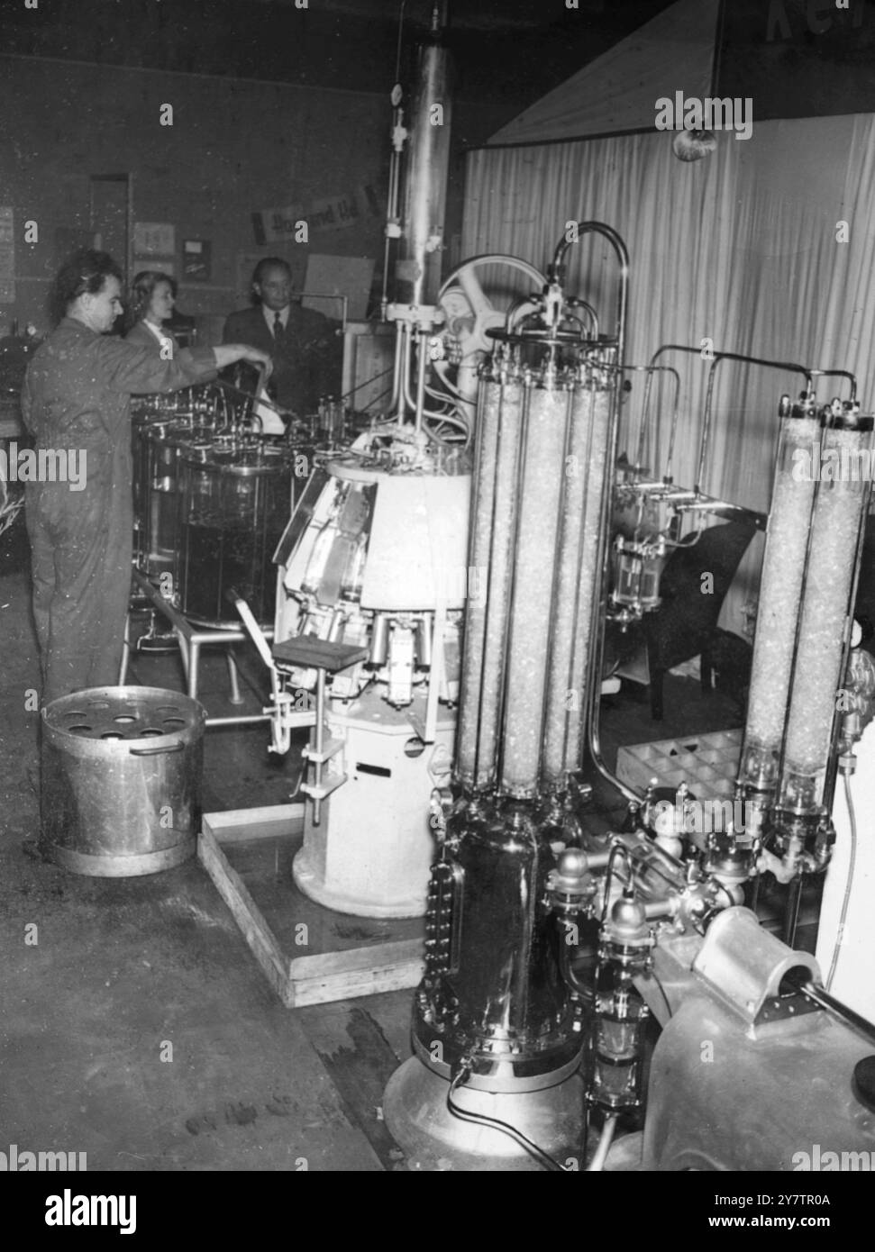 Auf der aktuellen Nürnberger Erfindungsmesse wird diese „Abfüllstation“ für Flaschen gezeigt. Sie besteht aus Glas, so dass der gesamte Prozess deutlich sichtbar ist. Ein Zylinder liefert die Flüssigkeit, die exakt in der richtigen Menge gemessen wird, vom rechten Gerät. Die Flüssigkeit wird dann mit Wasser verdünnt und durch die Zylinder im rechten Vorderboden mit Säure angereichert. 15. Juli 1950 Stockfoto