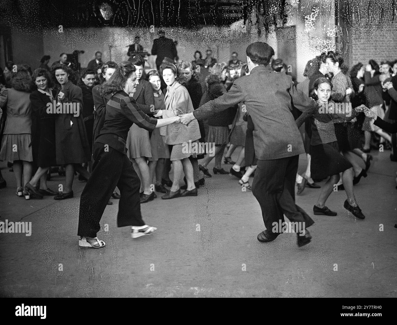 Das Tanzen im Park für Holidays-at-Home, der während des Krieges beliebt war, wird dieses Jahr vom London County Council wieder ermutigt. In den Sommermonaten wurden Opern, Theaterstücke und Tanz in Londoner Parks veranstaltet, und die ersten Aufführungen wurden von der Öffentlichkeit gut aufgenommen. Fotoshows: Im Victoria Park , Hackney , East London , zieht Musik aus dem Pavillon junge Tänzer zu einem London County Council Holidays-at-Home-Programm am 16. Juni 1945 an Stockfoto