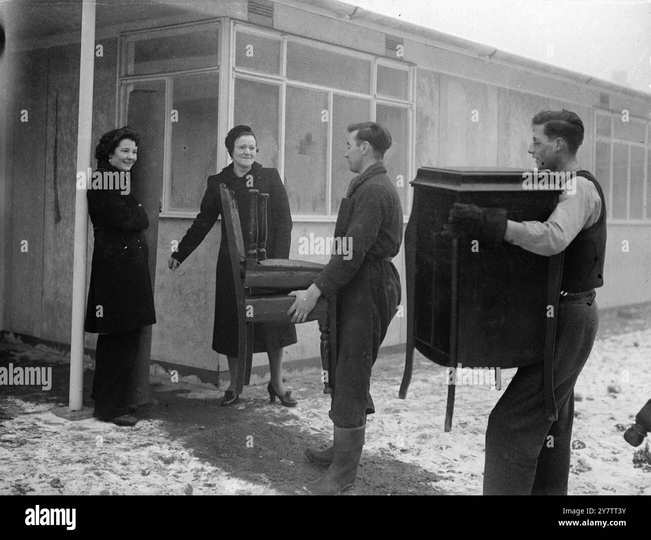Das erste Fertighaus von Sandys wurde von Mrs. Mary Dyett, ihrem Ehemann und ihrer 17-jährigen Tochter Eileen bewohnt, seit Mr. Duncan Sandys Lord Portall übernahm. Bis sie in ihr neues Haus zogen , das eine von sechs vorgefertigten Wohnungen auf einem Bombengelände in der Thames Street, Greenwich, Südost-London ist, hatte die Familie Dyett, die aus ihrem eigenen Haus bombardiert wurde, in öffentlichen Notunterkünften geschlafen. Fotoshows: George Dyett (Mitte) und ein Freund tragen Möbel in das Fertighaus. Mrs. Dyett und ihre Tochter Eileen sind es Stockfoto