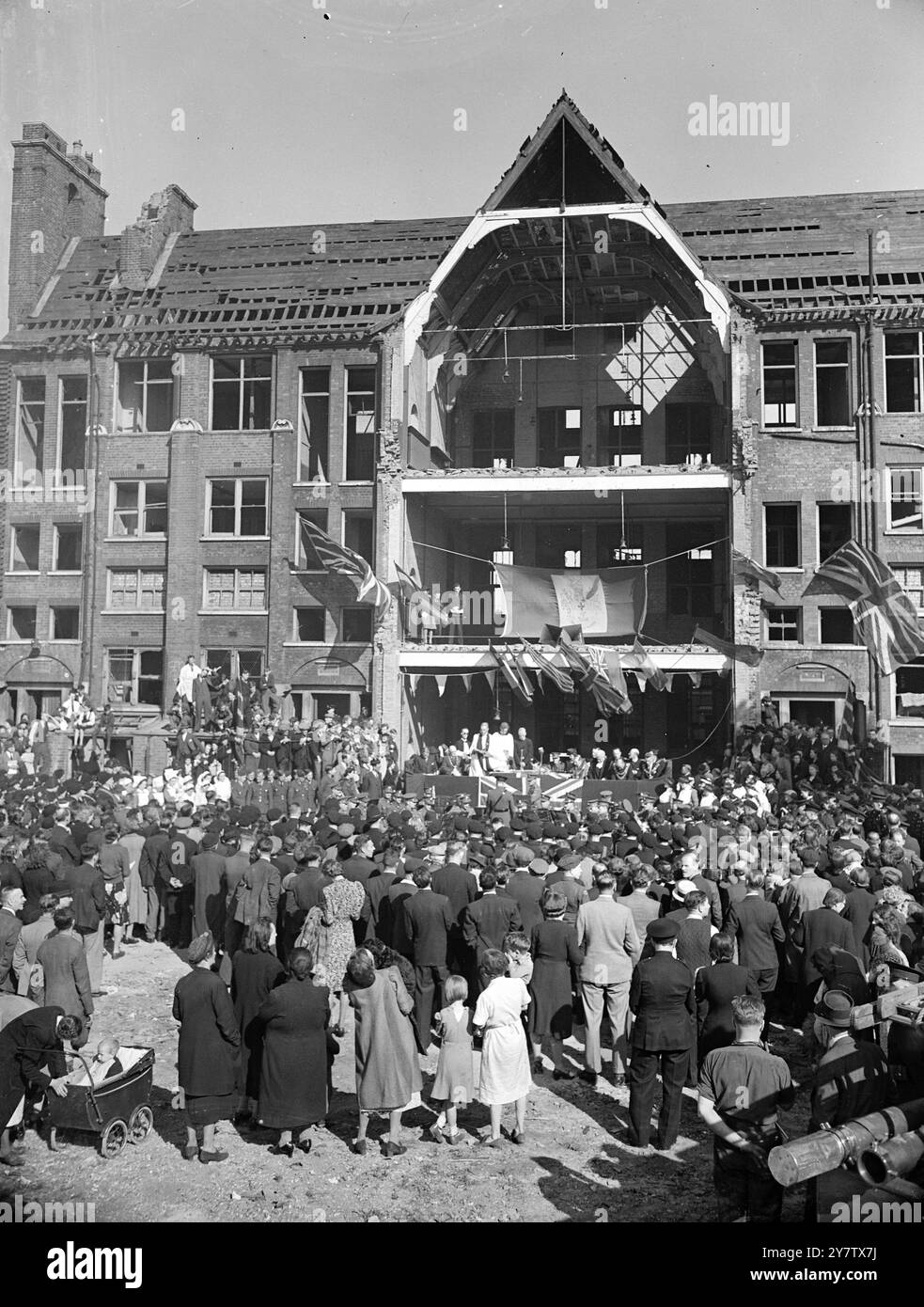 EAST LONDON FEIERT DEN ZWEITEN JAHRESTAG DER SCHLACHT UM GROSSBRITANNIEN anlässlich des zweiten Jahrestages der Schlacht um Großbritannien besuchte das Volk von Stepney, einem sehr stark verwüsteten Gebiet im East End von London, den Dienst ihres Rektors, Reverend Reginald French, in den Ruinen einer verwüsteten Schule im Distrikt, um dem Mut der RAF-Männer zu gedenken, die London in der Schlacht um Großbritannien verteidigten. Foto zeigt: Eine allgemeine Ansicht des Gottesdienstes vor der geschädigten Schule in Stepney. 15. September 1942 Stockfoto