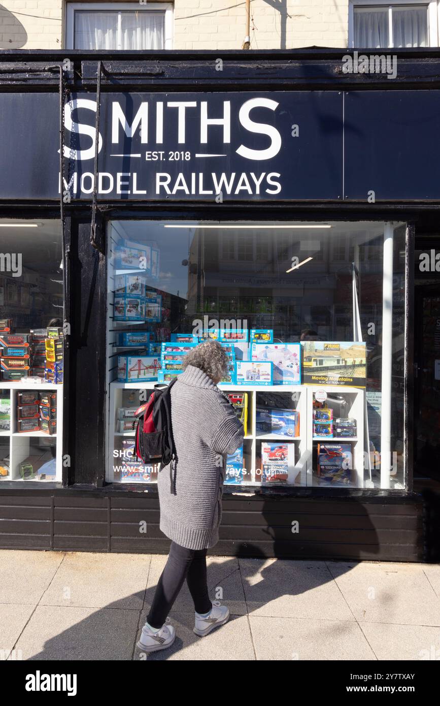 Eine Frau außerhalb des Shops von Smiths Model Railways, einst ein beliebtes Hobby; Sheringham, Norfolk England, Großbritannien Stockfoto