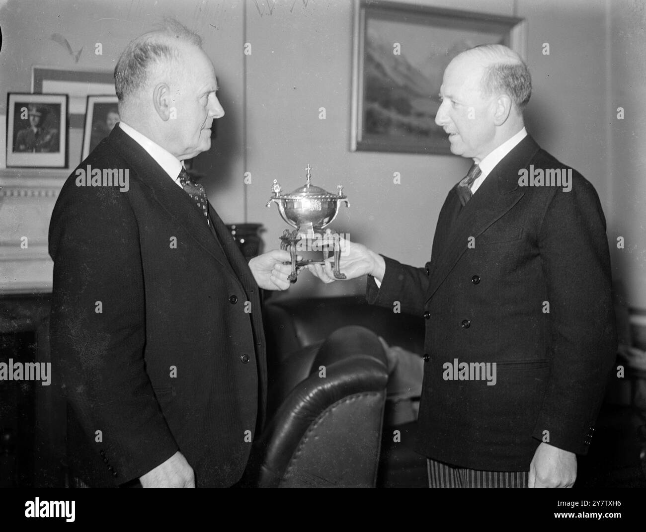 NEW ZEALAND HIGH COMMISSIONER ERHÄLT SILBERNE LAMPE; GESCHENK AN NEW ZEALAND LONDONERS LEAGUE Foto zeigt: Sir George Wilkinson, ehemaliger Lord Mayor of London, überreicht Herrn W J Jordan, dem Hohen Kommissar für Neuseeland in London, eine silberne Lampe. Die Silberlampen sind das Ergebnis eines Briefes, den Sir George Wilkinson von einem Bankbeamten in Wellington, Neuseeland, erhielt, der eine Londoners League gegründet hatte. Auf der einen Seite der Lampe befindet sich das Wappen von Neuseeland, auf der anderen das Wappen von london. Auf der Oberseite ist die Musik der Schallen von Bow Bells graviert – und die Basis ist gefertigt Stockfoto