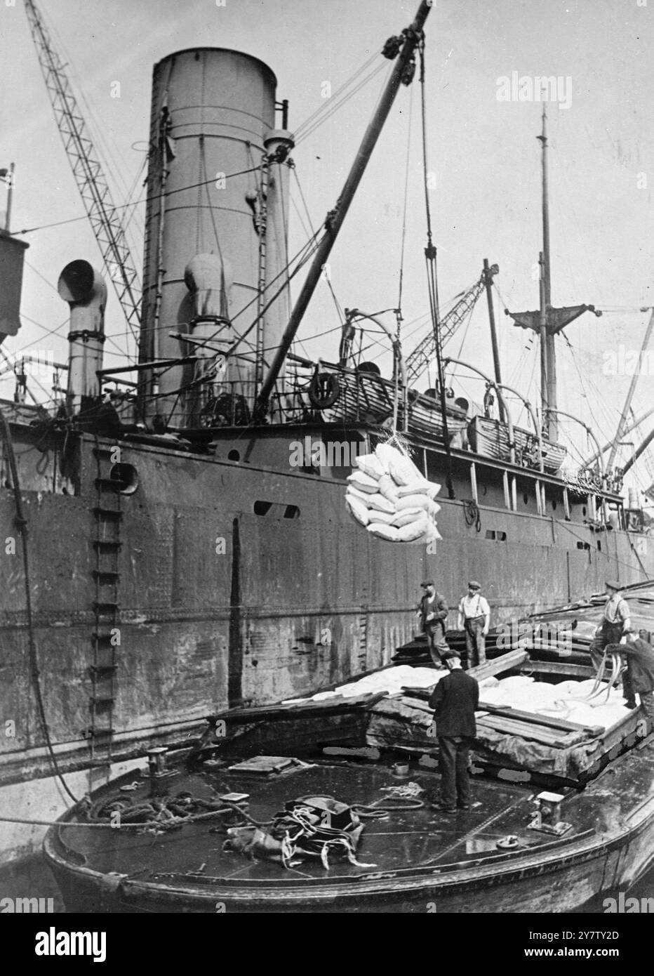 ESSEN AUS AMERIKA KOMMT IN GROSSBRITANNIEN AN Foto zeigt: Säcke mit kanadischem Weizen werden in ein Lastkahn gesenkt. Der Weizen war Teil einer Fracht aus getrockneter Milch, Mehl kanadischem Weizen, Käse, Schmalz, Rotem Kreuz-Waren und anderen Waren, die von einem britischen Schiff aus Amerika gebracht wurden. Einige der Waren wurden unter dem Lease Lend Bill verschickt, andere vom amerikanischen Volk. Stockfoto