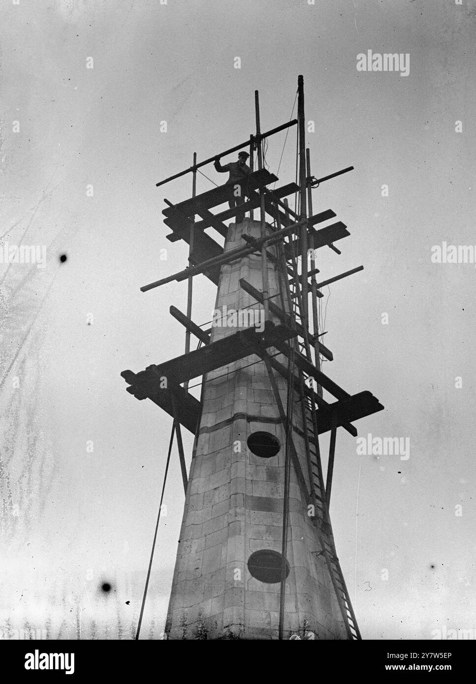 COLD WORK Photo zeigt: Steeplejack Bill Collins trotzt Jack Frost und setzt mit einem der kältesten Jobs in london fort - die Sicherheit des bombenbeschädigten Turms der St. Botolph's Church, Aldgate, Mr collins lebt in der Pepper Street, SE 28. Dezember 1944 Stockfoto