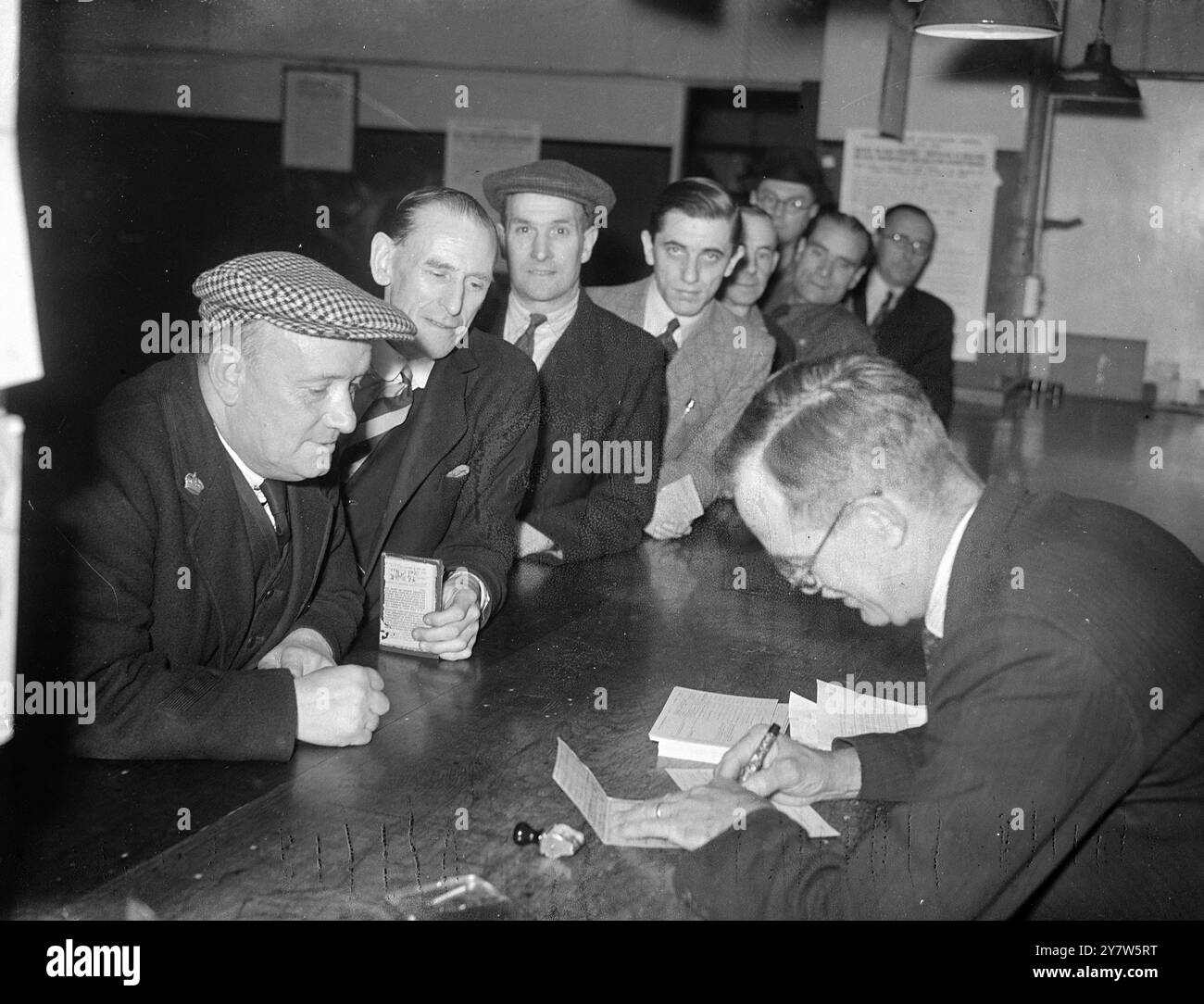 MOBILISIERUNG DER BAUHERREN alle Männer im Alter von 18 bis 60 Jahren, die früher in der hoch- und Tiefbauindustrie beschäftigt waren, müssen sich nun bei der Beschäftigungsbörse in ganz Großbritannien anmelden. Fotoshows: Herr H Mackenzie aus Peckham, heute Botschafter im Ministerium für Flugzeugproduktion und früher Arbeiter, meldet sich am 16. Juni 1945 bei anderen Männern an der Westminster (London) Employment Exchange an Stockfoto