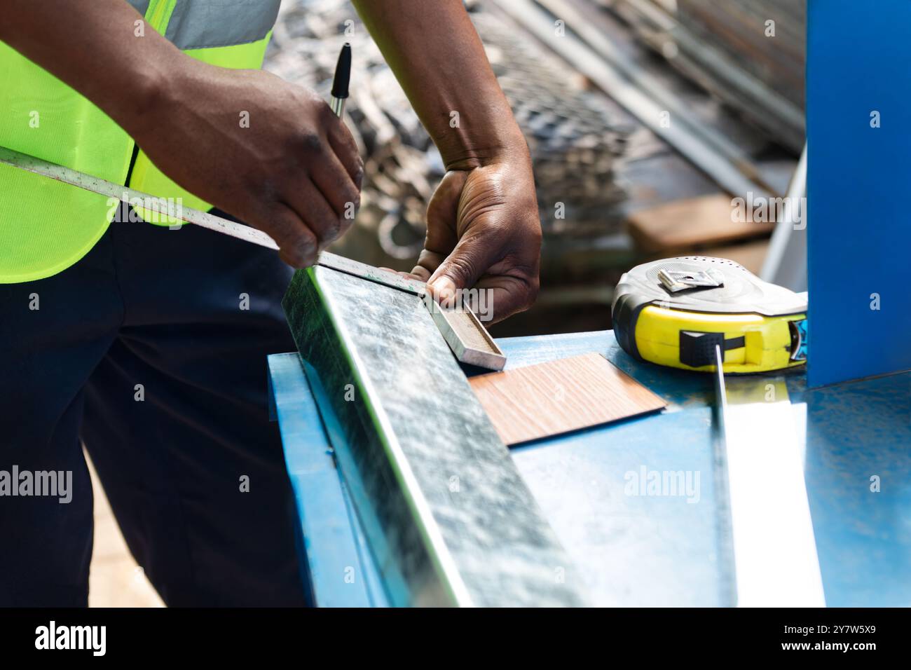 afroamerikanischer Arbeiter, der ein Vierkantrohr mit einem rechtwinkligen Lineal misst Stockfoto