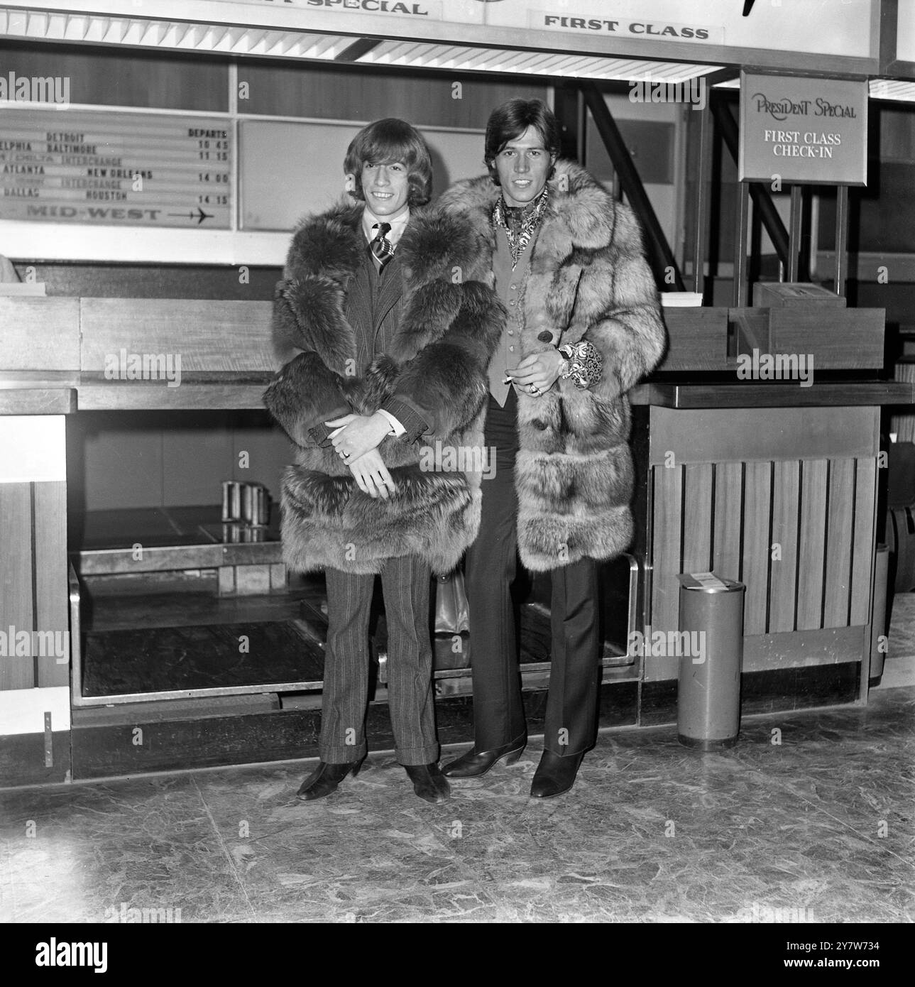 Robin (links) und Barry Gibb von der Popgruppe Bee Gees warten gut in Pelz eingewickelt auf ihren Flug am Flughafen London Heathrow. Sie gehen zurück nach Hause, mit der glücklichen Nachricht, dass ihr neuester Rekord „World“ immer noch in den Top-Ten-Charts steht. Eine Sache, die sie nicht brauchen, wenn sie am Ziel ankommen, ist ein Pelzmantel. Die beiden Mitglieder der fünf-Mann-Gruppe reisen nach Australien, derzeit mitten in einem heißen Sommer. 18. Dezember 1967 Stockfoto