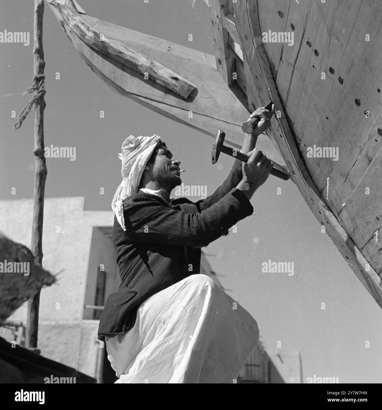 Katar - 1954 - - - ein arabischer Bootsbauer arbeitet am Heck einer Dau , die in einer Werft in Doha repariert wird . Stockfoto