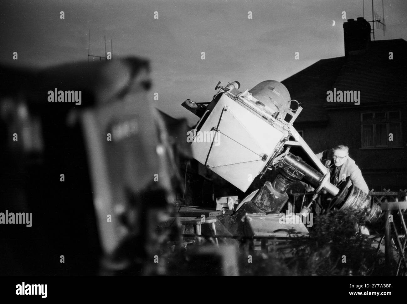 George Hole, einer der bekanntesten Astronomen Großbritanniens, fotografierte mit einem Teleskop, das er sich im Garten seines Hauses in Patcham, Sussex, England, manipulierte. Während die Welt den ersten Mann auf dem Mond im Fernsehen ansieht, hofft Mr Hole, einen Blick auf die Raketenfackeln zu erhaschen, während das Mondmodul von Apollo XI. Auf die Mondoberfläche im Meer der Ruhe ging. Der Mond ist neben dem Kamin von Mr. Holes Haus zu sehen. 21. Juli 1969 Stockfoto