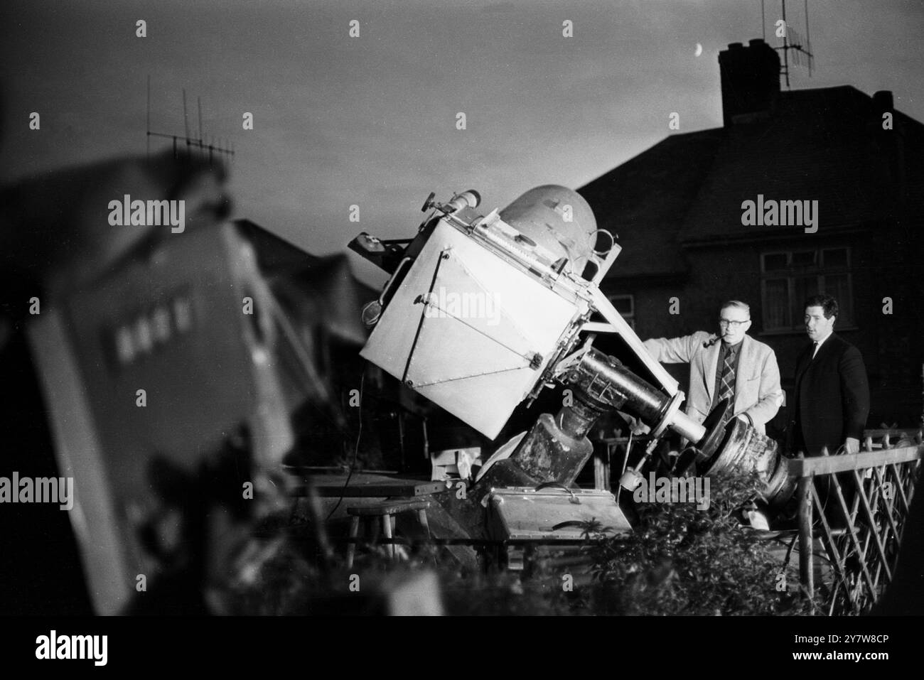 George Hole, einer der bekanntesten Astronomen Großbritanniens, fotografierte mit einem Teleskop, das er sich im Garten seines Hauses in Patcham, Sussex, England, manipulierte. Während die Welt den ersten Mann auf dem Mond im Fernsehen ansieht, hofft Mr Hole, einen Blick auf die Raketenfackeln zu erhaschen, während das Mondmodul von Apollo XI. Auf die Mondoberfläche im Meer der Ruhe ging. Der Mond ist neben dem Kamin von Mr. Holes Haus zu sehen. 21. Juli 1969 Stockfoto