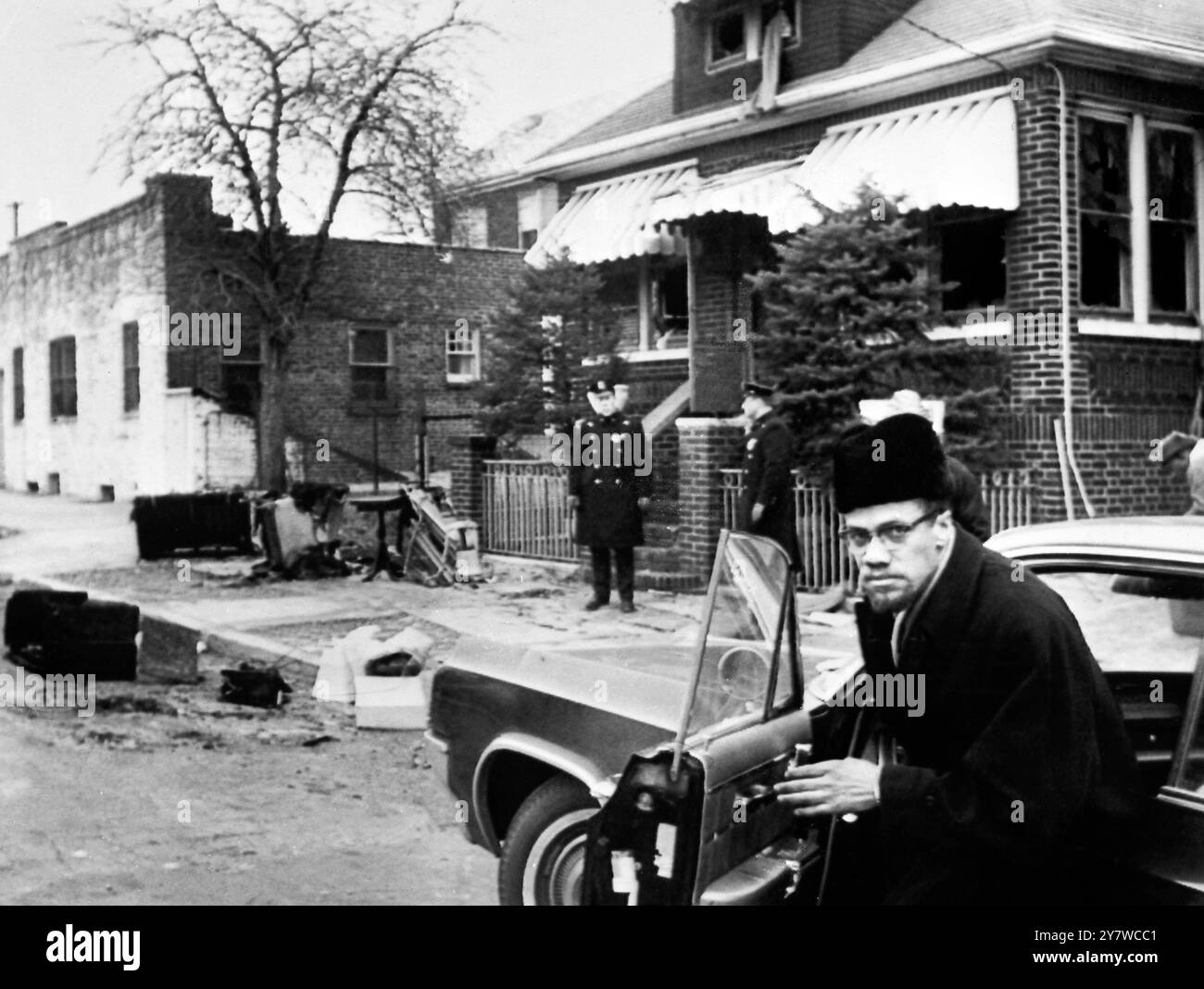 Malcolm X Home bombarbedNew York : Malcolm X kehrt heute in sein Haus zurück, nachdem eine Brandbombe in das Haus geworfen worden war, während der schwarze nationalistische Führer , seine Frau und vier Töchter darin schliefen. Malcolm , seine Frau und seine Töchter wurden nicht verletzt , aber das Haus erlitt schwere Schäden durch Feuer und Rauch . Verbrannte Möbel und Haushaltsgegenstände verstreuen die Straße. Die Polizei sagte, sie hätten keine Hinweise auf die Identität des Bombenwerfers. Nur wenige Stunden nachdem Malcolm von einer Reise nach England zurückgekehrt war, wurde die Bombe ins Haus geworfen. 14. Februar 1965 Stockfoto