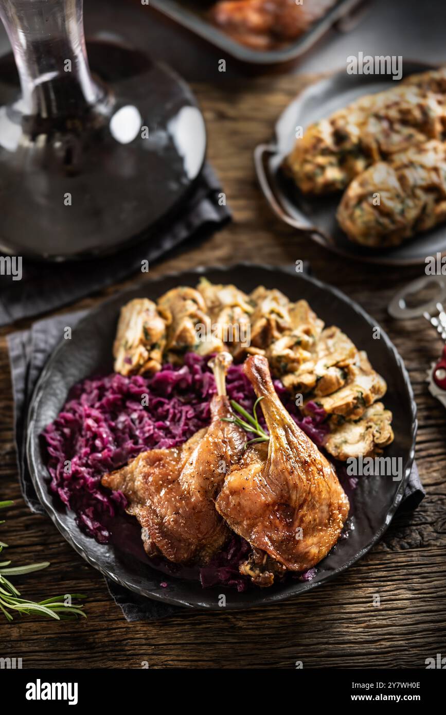 Teil der Gebratene Entenkeule, Rotkohl hausgemachte Knödel auf dem Teller und Rotwein auf dem Hintergrund. Stockfoto