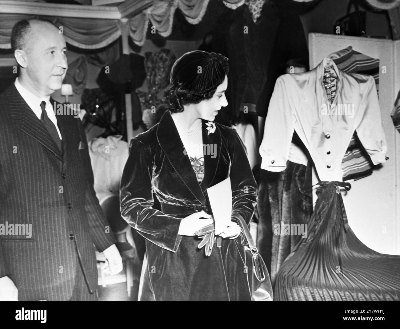 Während ihres Besuchs in Paris besuchte Prinzessin Margaret eine von Diors regelmäßigen Nachmittagsmodenschauen. Die Prinzessin trug Hut , Mantel und Kleid aus rubinrotem Samt . Fotoshows - Prinzessin Margaret mit Christian Dior gesehen, wie sie eines seiner Entwürfe bewundert. November 1951 Stockfoto