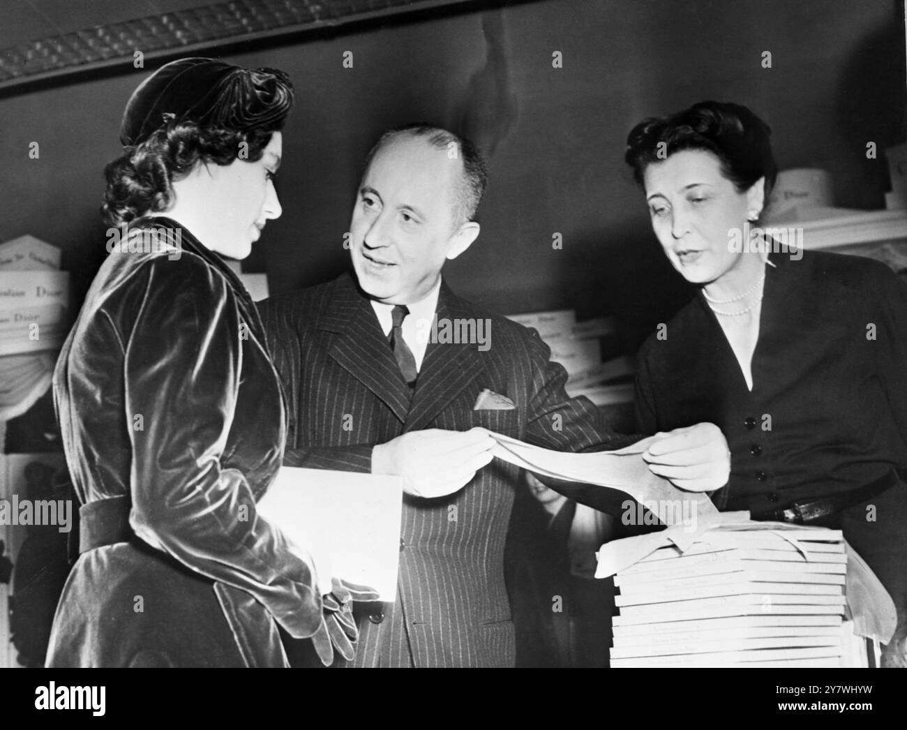 Prinzessin Margaret besuchte den Modesalon des berühmten Christian Dior . Dort wurde ihr ein Paar Nylons vom Modekönig angeboten. Ein unbenannter Assistent schaut zu. November 1951 Stockfoto