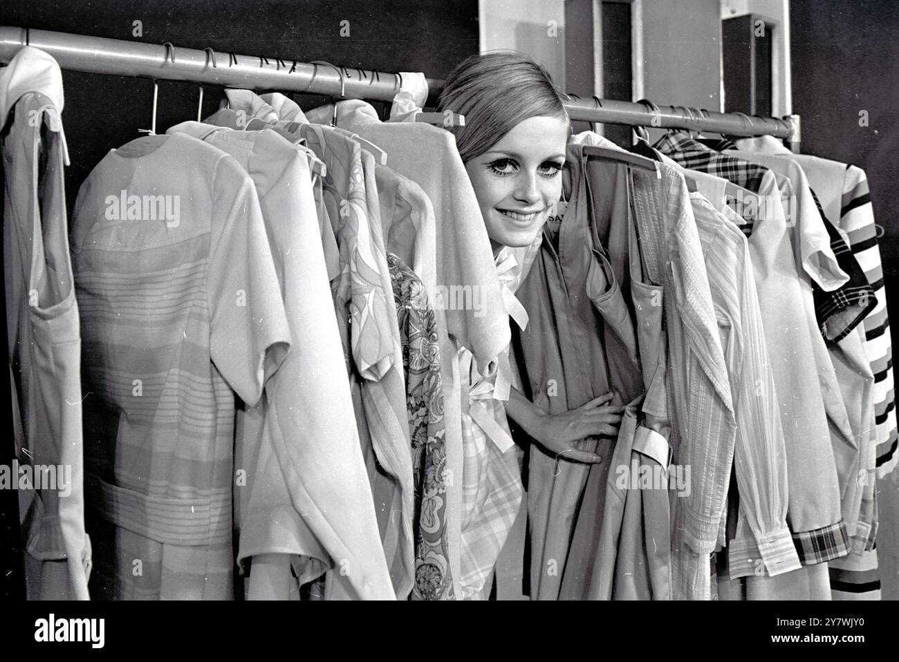 Erkennen Sie das Gesichter zwischen den Schienen modischer Kleidung, es gehört zum Modemodell Twiggy . " Twiggy Collection " wird von den Bekleidungsherstellern Leonard Bloomberg und Sidney Ellis ins Leben gerufen . Sie wurde bei Twiggy Models im West End fotografiert. Februar 1967 Stockfoto