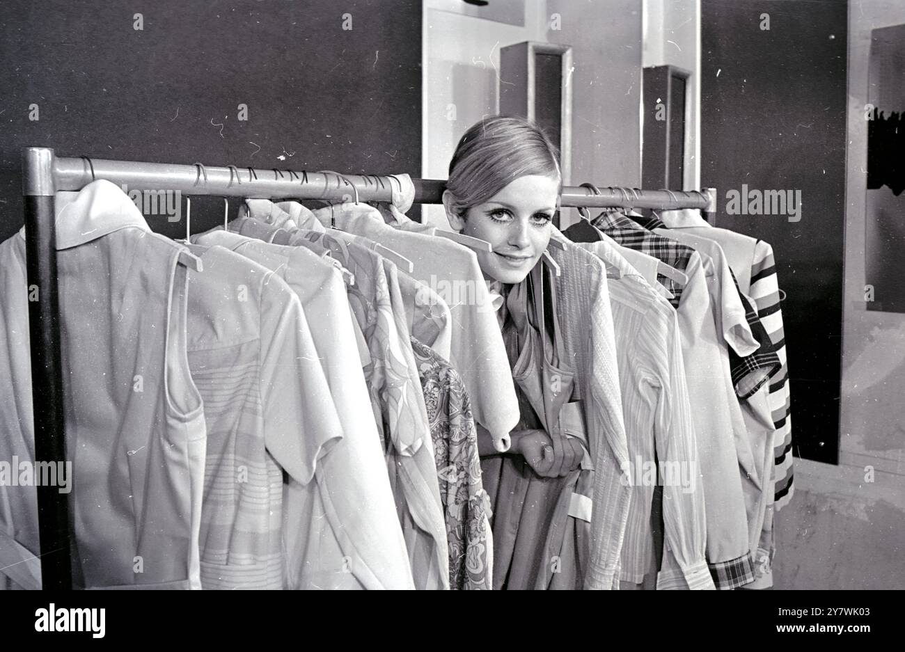Erkennen Sie das Gesichter zwischen den Schienen modischer Kleidung, es gehört zum Modemodell Twiggy . " Twiggy Collection " wird von den Bekleidungsherstellern Leonard Bloomberg und Sidney Ellis ins Leben gerufen . Sie wurde bei Twiggy Models im West End fotografiert. Februar 1967 Stockfoto