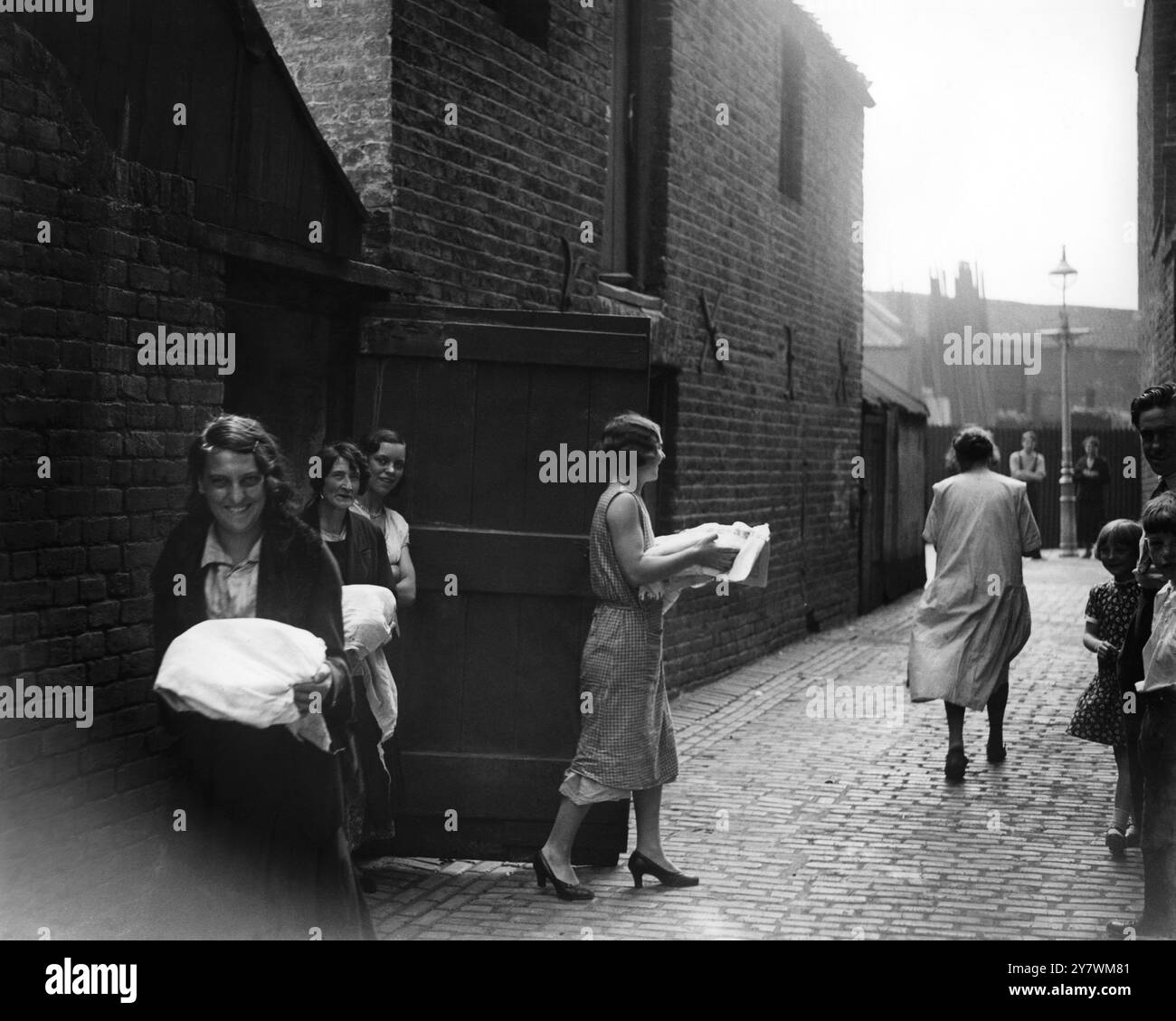 Damen kochen Abendessen in den Gemeinschaftsöfen im East End von London von der Restwärme im Backofen 1933 ©TopFoto Stockfoto