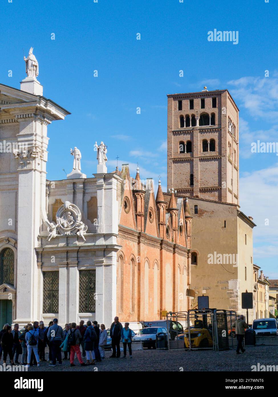 Mantua, Italien 30. September 2024 Touristen lauschen einem Reiseleiter auf der piazza Sorsoana, mit der Kathedrale und dem Uhrenturm im Hintergrund Stockfoto