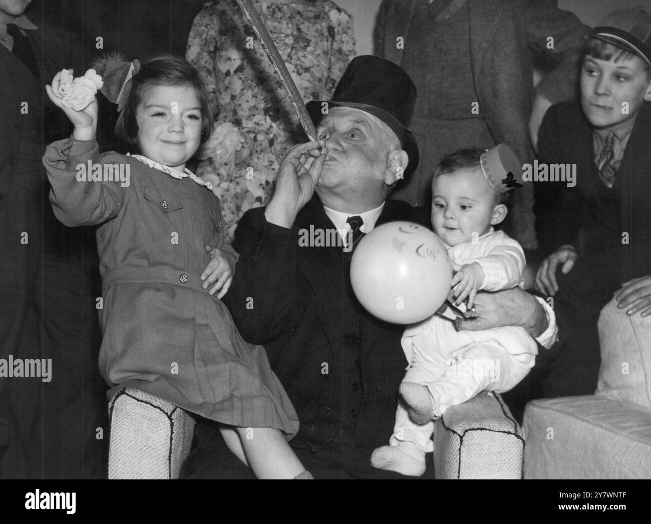 George Lansbury , 78 Jahre alter Abgeordneter von Bow , nahm an einer Familienfeier Teil , die im Haus von Mrs. Postgate , der Tochter von Mr Lansbury , in Hendon, England stattfand . Das Bild zeigt Herrn Lansbury , der seinen Urenkel Nigel Whiskin und seine Enkelin Moyna Taylor auf der Party amüsiert . 27. Dezember 1937 Stockfoto